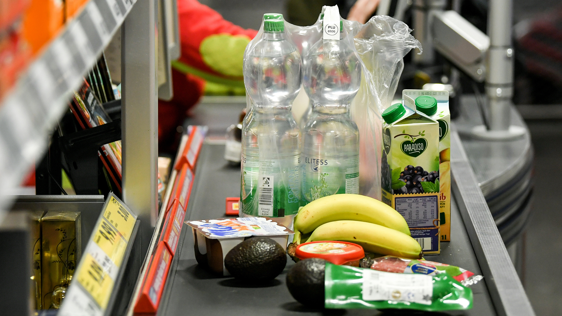 Lebensmittel liegen auf dem Band an einer Kasse in einem Supermarkt.