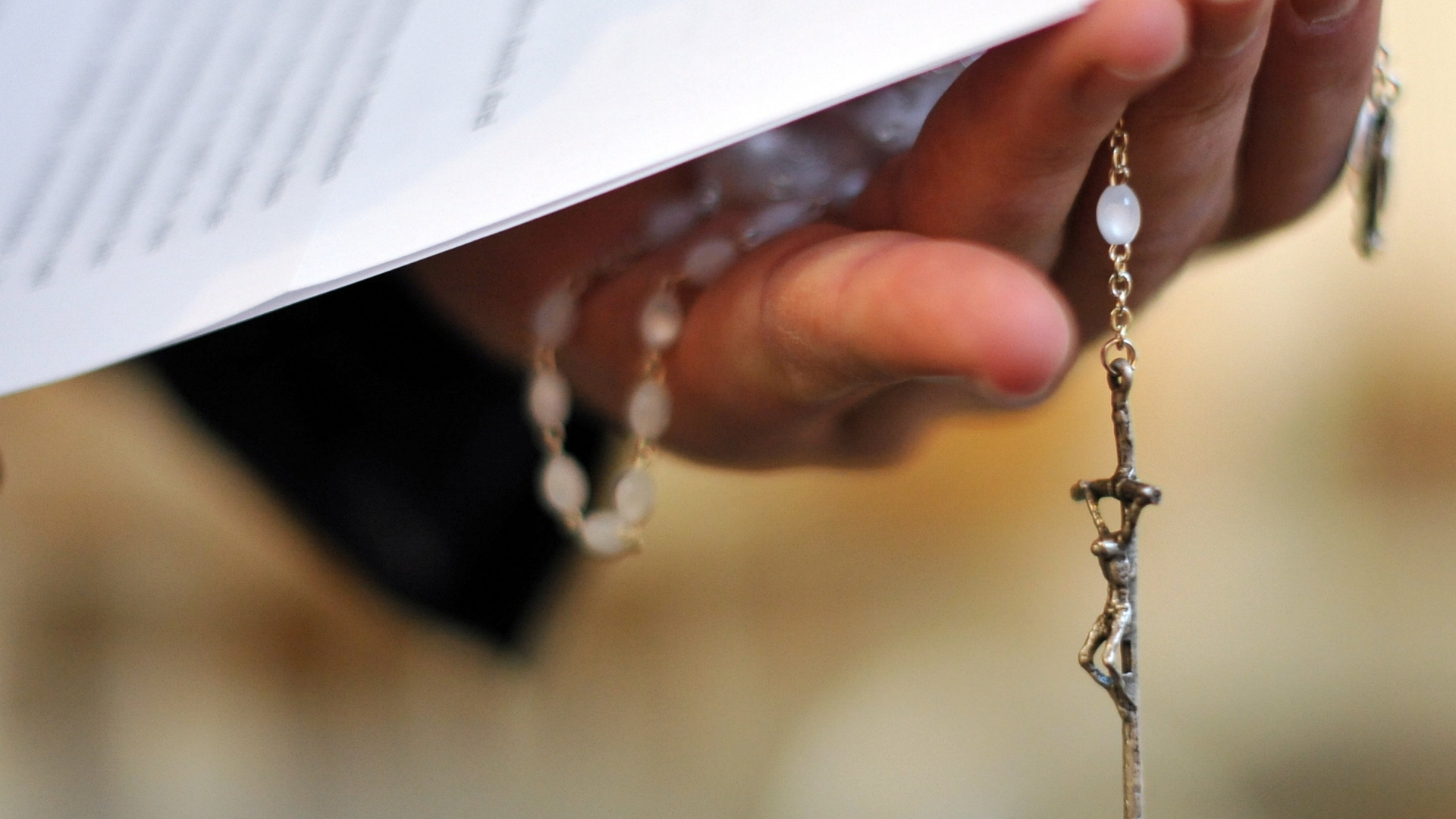 Ein Priester hält einen Rosenkranz und eine bischöfliche Erklärung zu den Missbrauchsfällen durch Jesuiten-Pater in der Hand. | Bildquelle: dpa