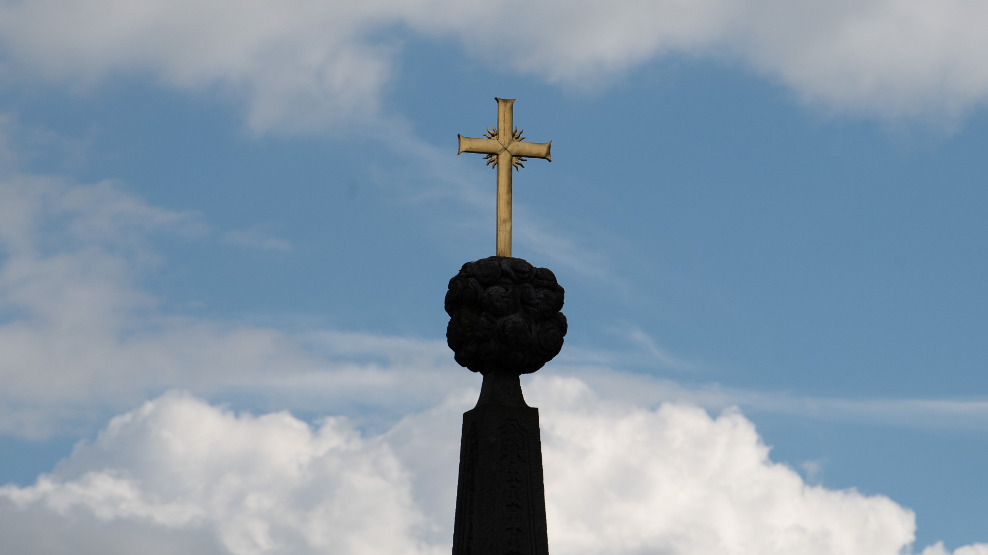 Wolken ziehen hinter einem Kreuz am Dom St. Salvator zu Fulda vorbei.