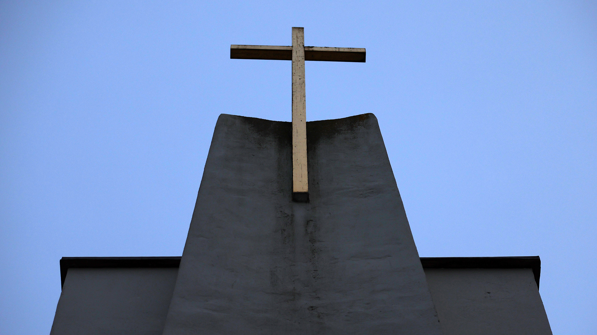 Ein Kreuz ist an der Fassade einer katholischen Kirche zu sehen.