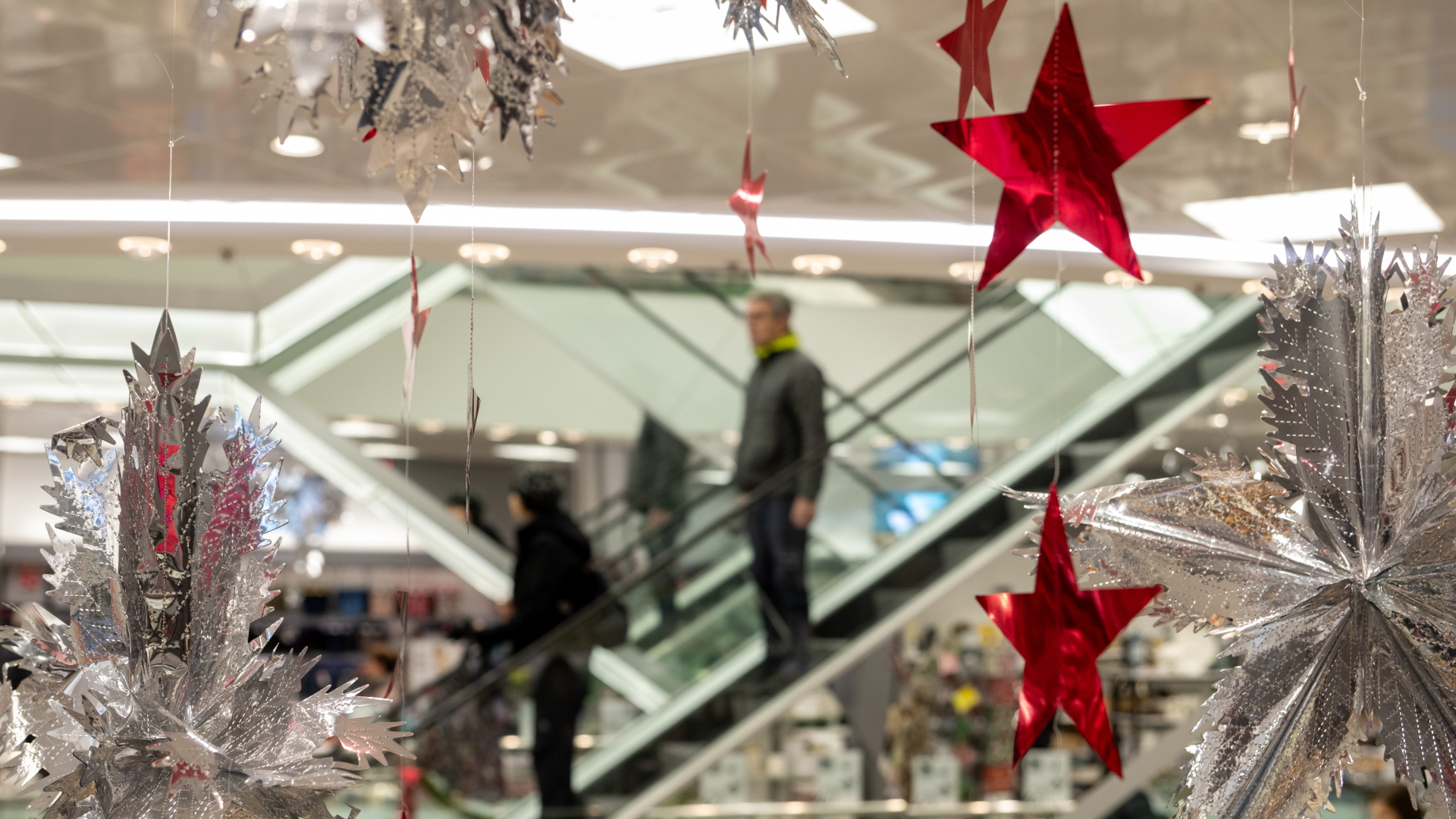 Kunden fahren auf Rolltreppen durch ein weihnachtlich dekoriertes Kaufhaus