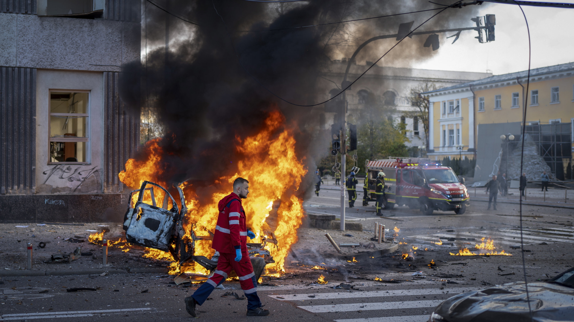 Ein Feuerwehrmann läuft an einem brennenden Auto in Kiew vorbei. | AP