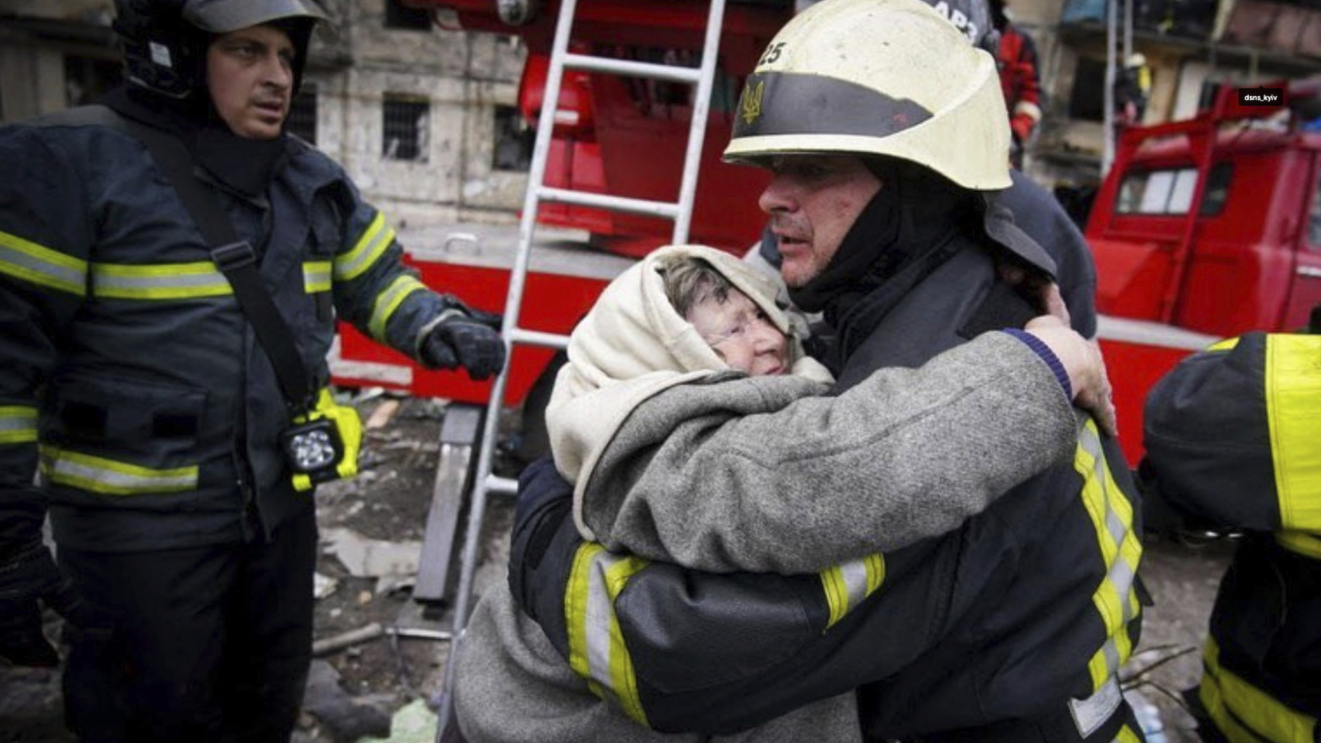 Ein Feuerwehrmann umarmt eine Frau in Kiew, Ukraine. | AP
