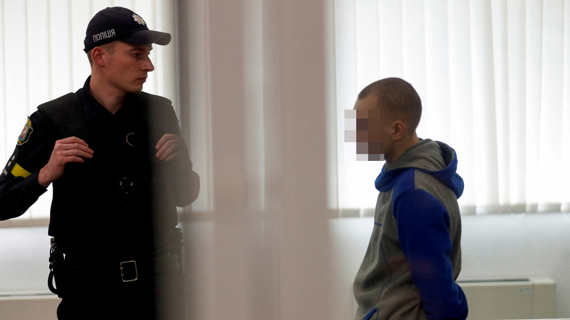 Ein Polizist blickt zu dem Angeklagten in einem Gericht in Kiew, Ukraine, nachdem dieser zu lebenslanger Haft verurteilt wurde. | REUTERS