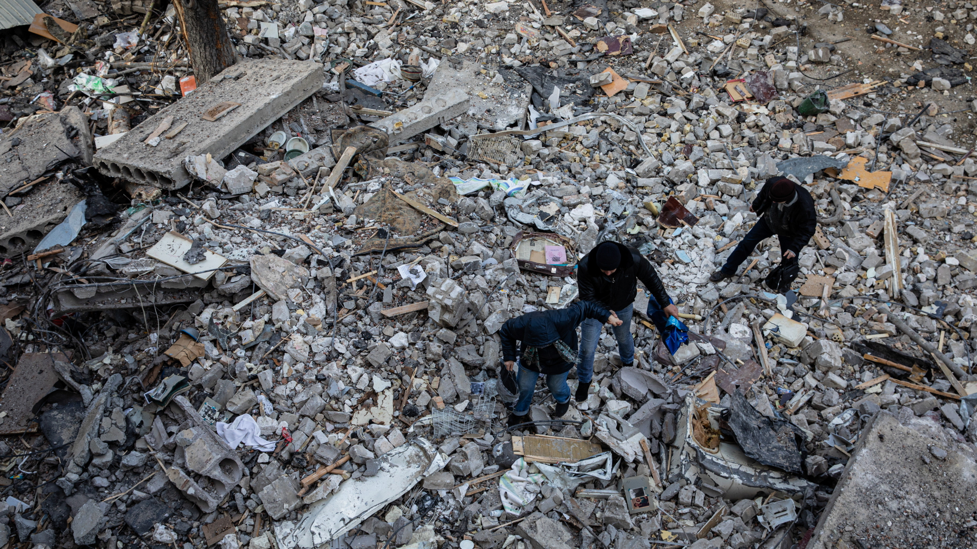 Drei Menschen bahnen sich einen Weg durch Schutt und Trümmer in Kiew.