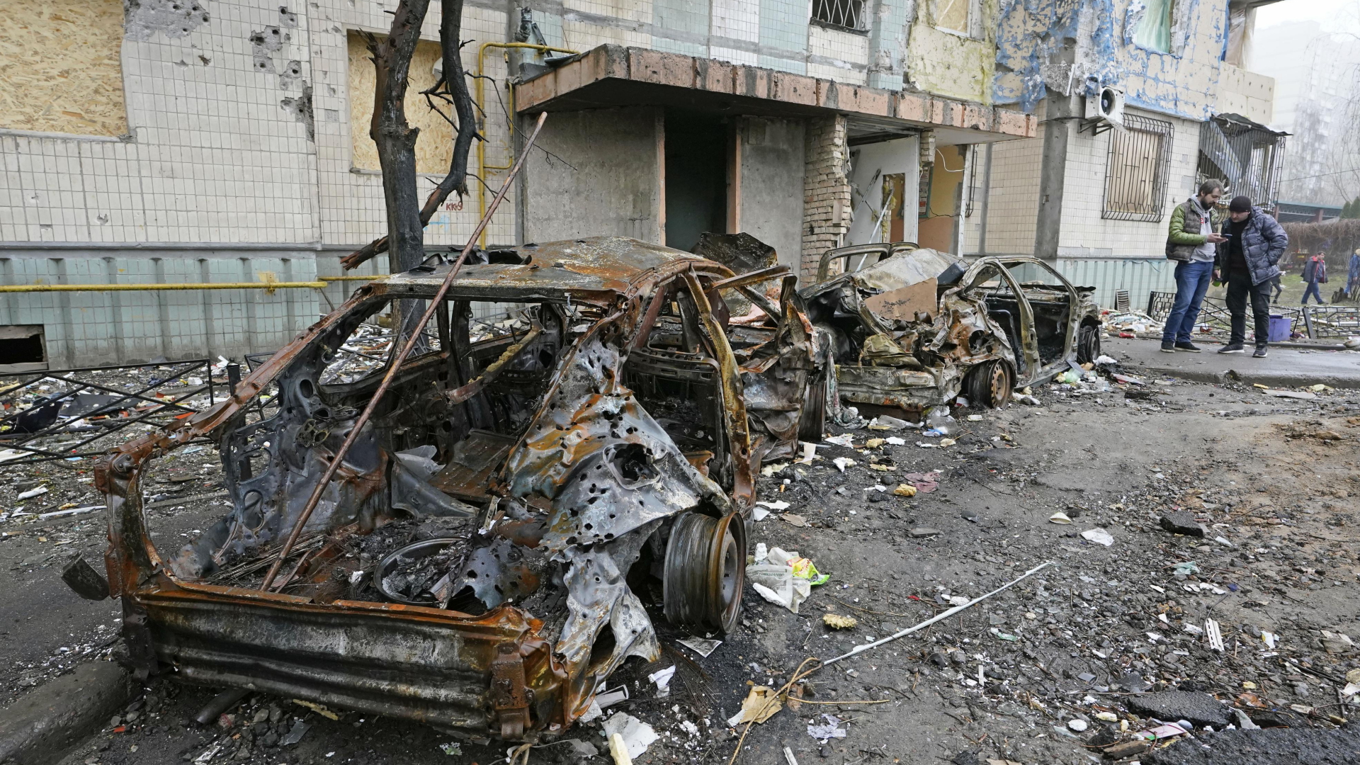 Ein verbranntes Fahrzeug steht nach einem russischen Raketenangriff vor einem beschädigten Gebäudekomplex in Kiew. | dpa