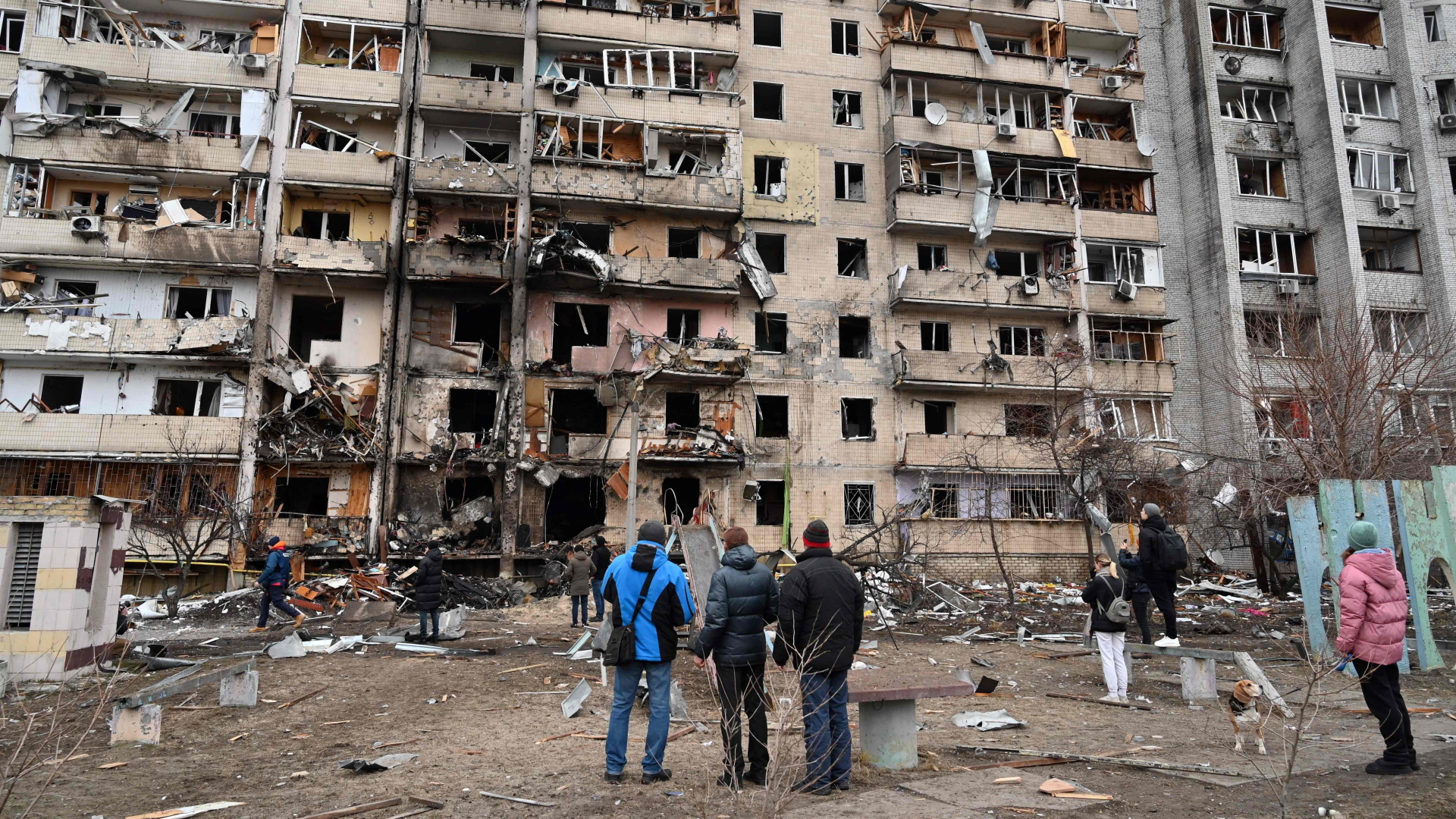 Menschen schauen auf ein beschädigtes Wohnhaus in einem Vorort der ukrainischen Hauptstadt Kiew. | AFP