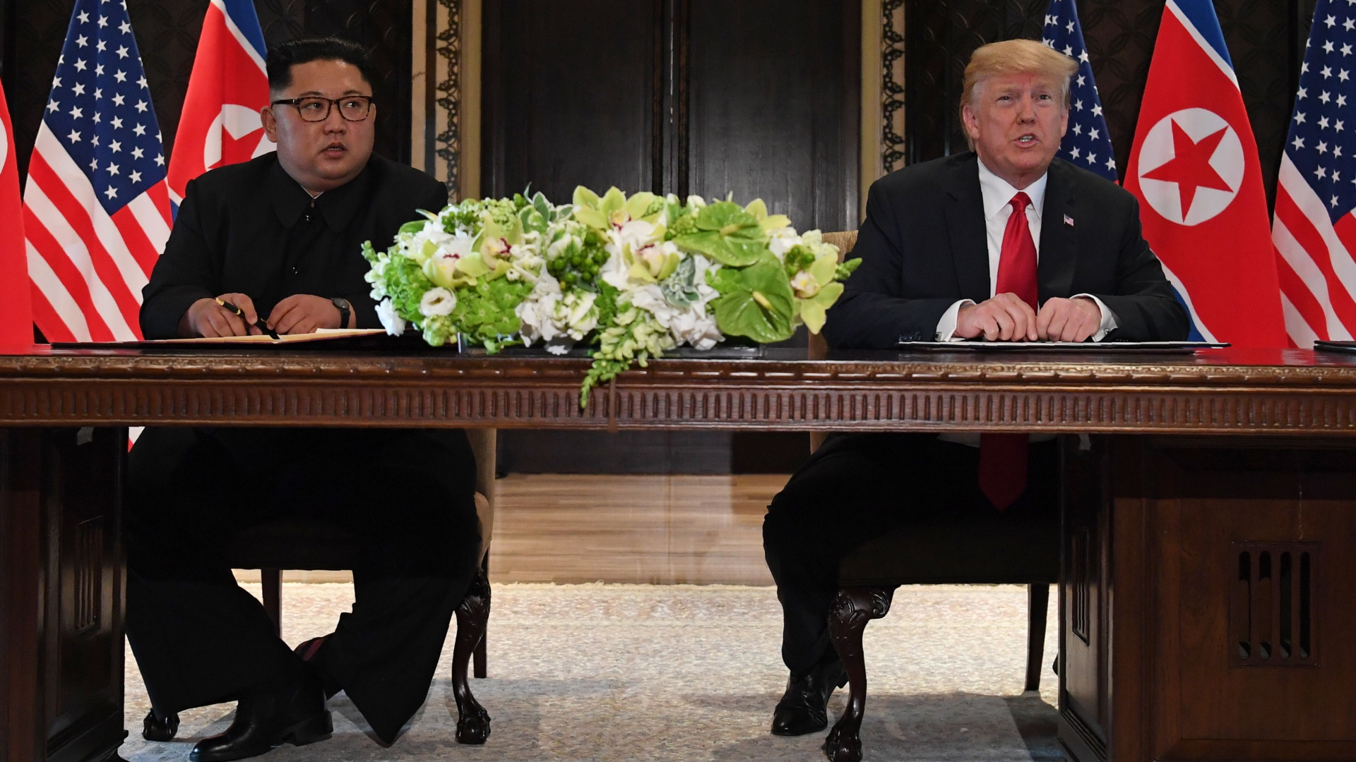 Nordkoreas Staatschef Kim Jong Un und US-Präsident Trump sitzen nebeneinander am Tisch.