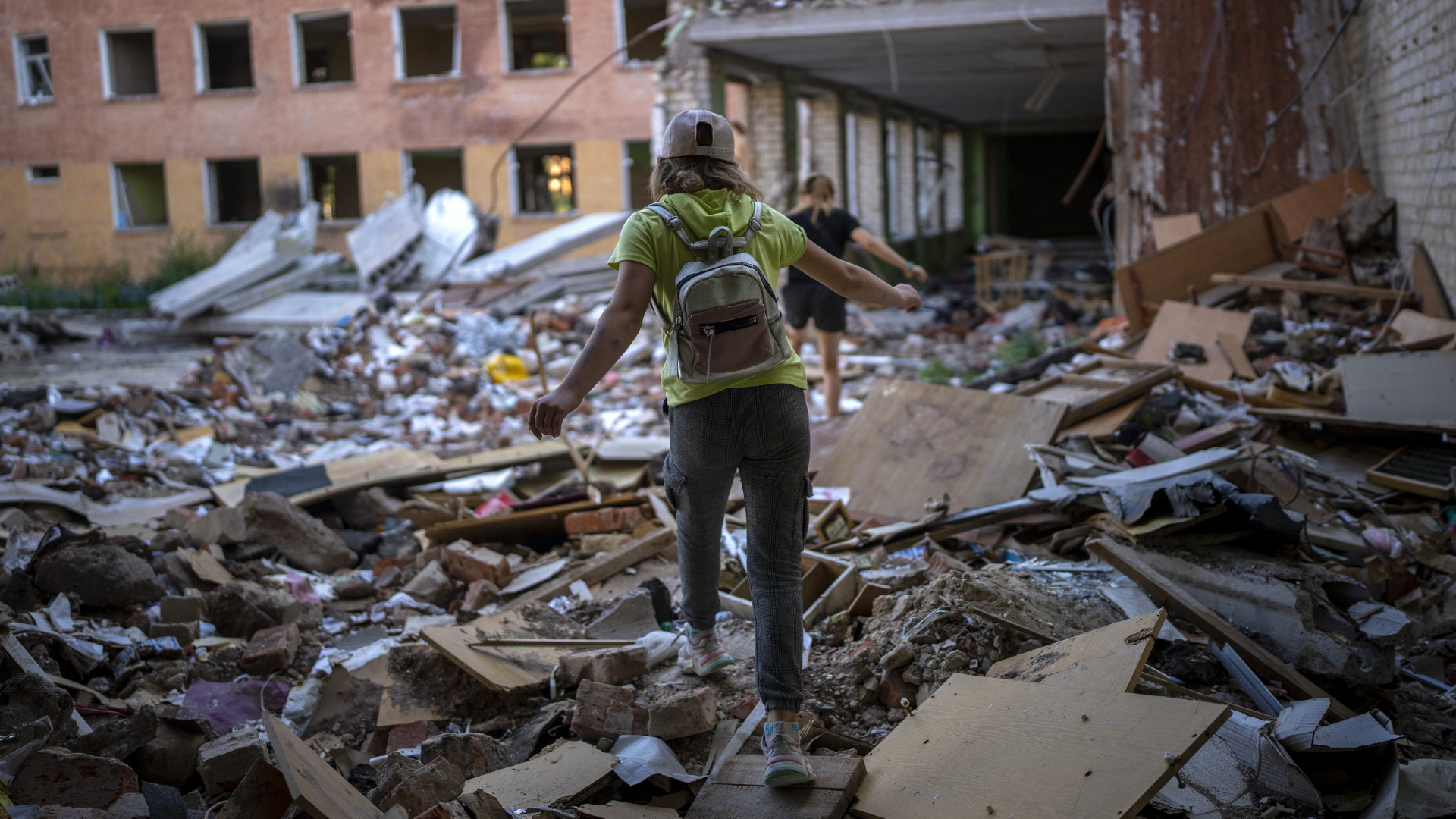 Eine Schülerin geht auf den Trümmern einer Schule in Tschernihiw (Ukraine), die von russischen Streitkräften bombardiert wurde. | Emilio Morenatti/AP/dpa