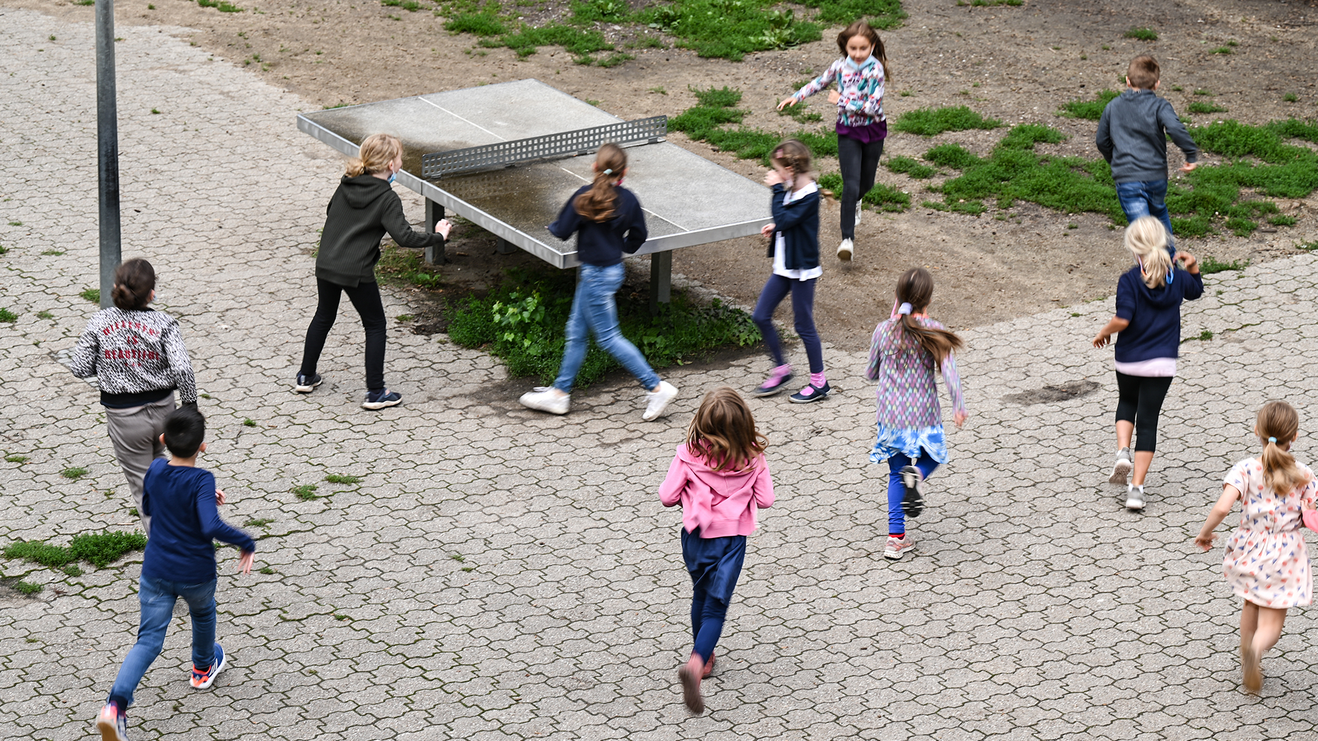 Schülerinnen und Schüler einer Grundschule laufen auf einem Schulhof um eine Tischplatte | picture alliance/dpa