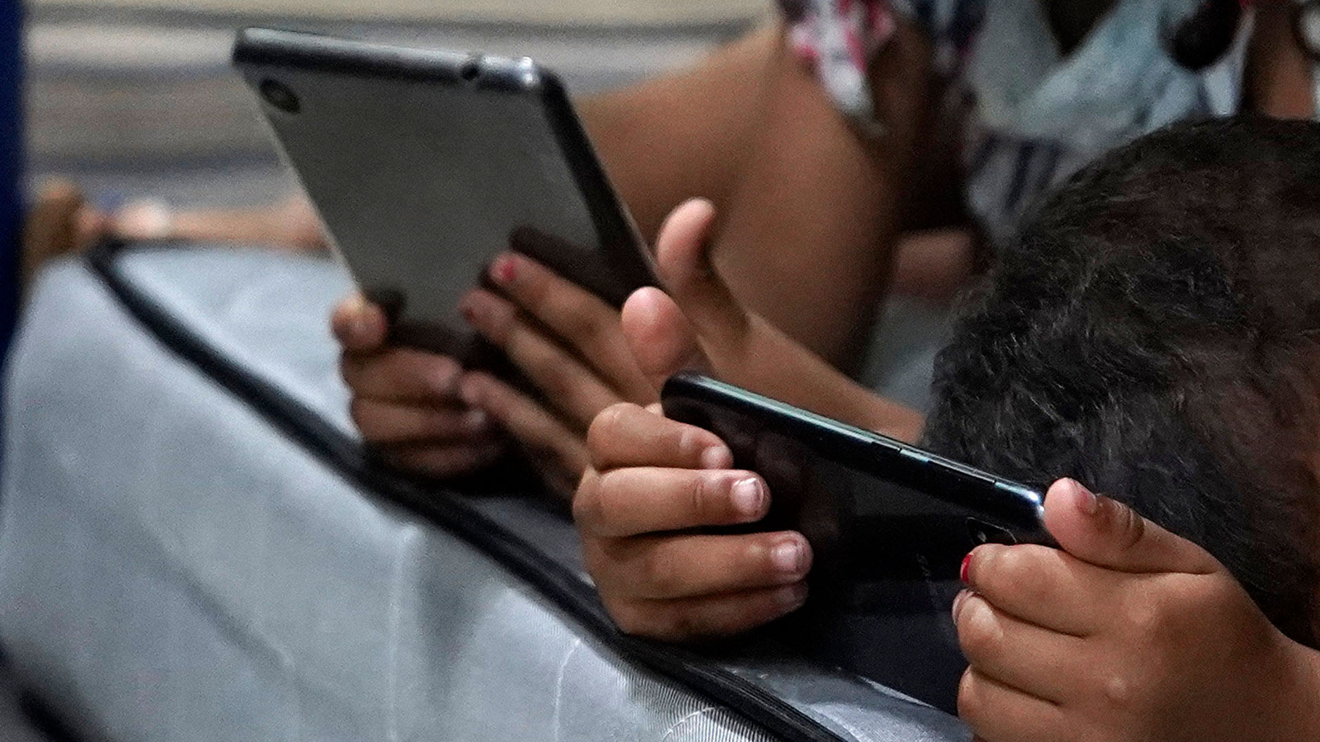 Kinder liegen in Mexiko mit Smartphones auf einem Bett. (Archivbild: 19.05.2021) | picture alliance / NurPhoto