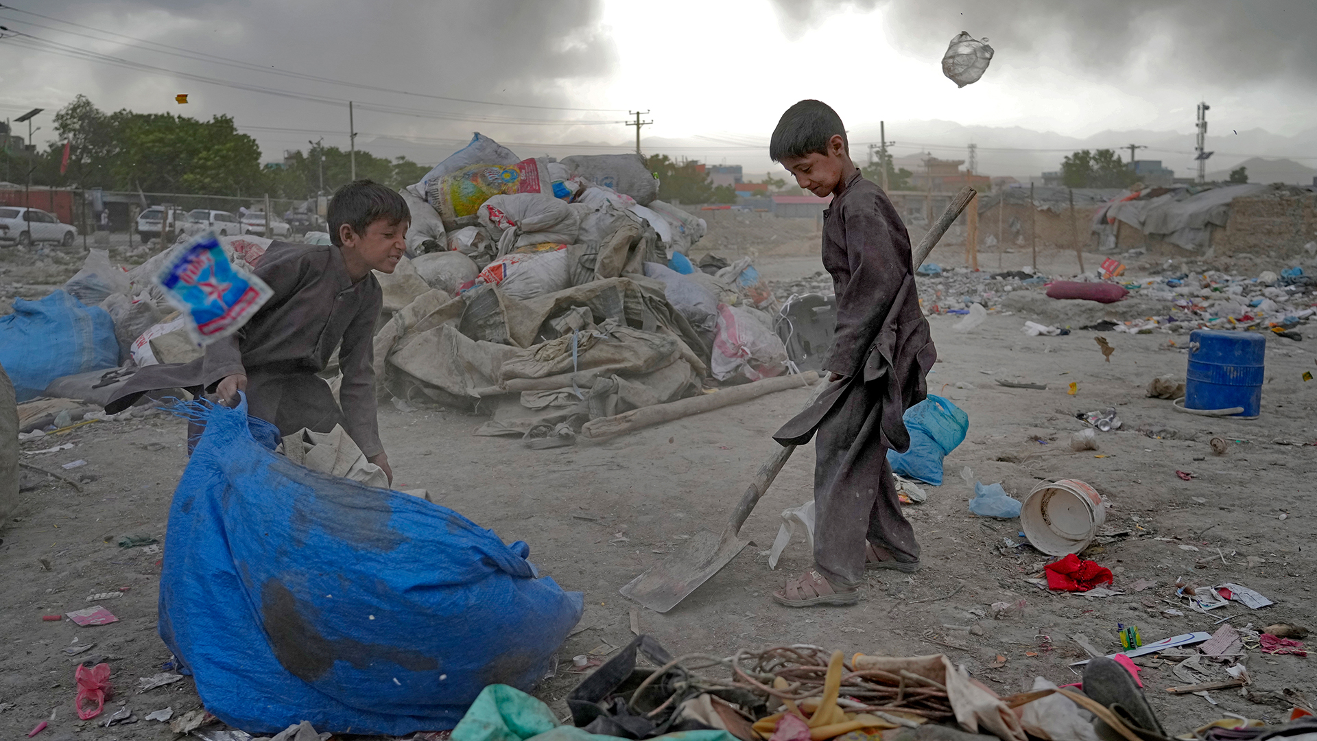 Zwei afghanische Kinder sammeln wiederverwertbares Material von einer Müllhalde. | dpa