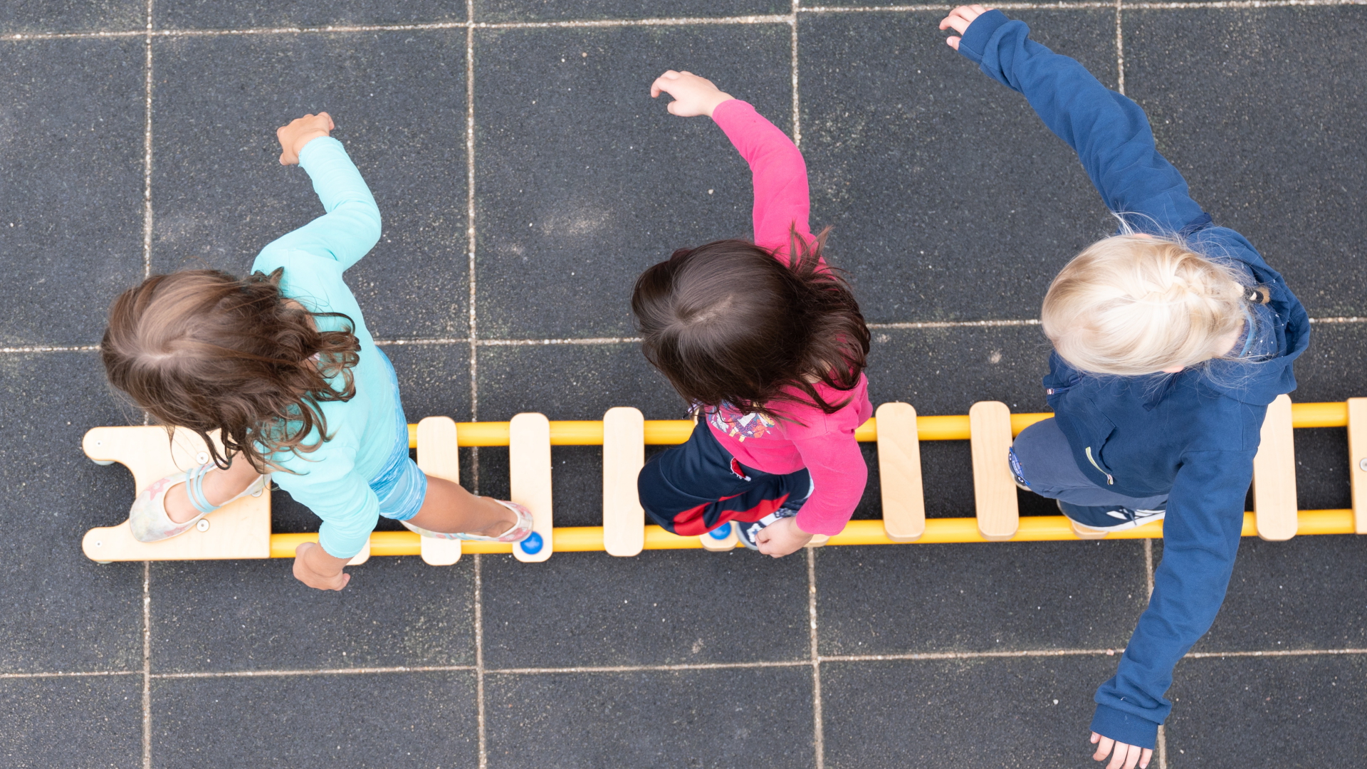 Kinder balancieren auf dem Spielplatz einer Kindertagesstätte im sächsischen Dresden auf einem Brett. | dpa