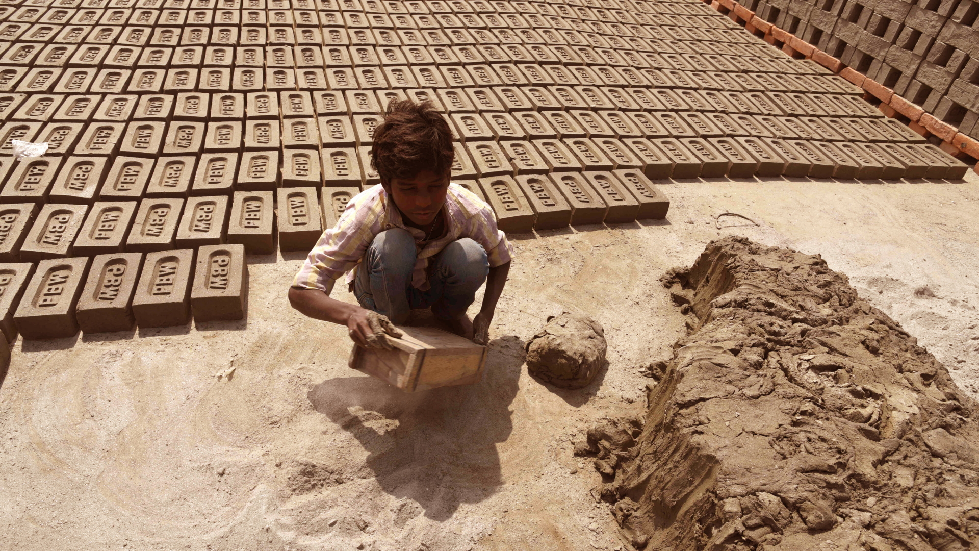 Ein Junge arbeitet in Kalkutta (Indien) in einer Ziegelsteinfabrik. | dpa