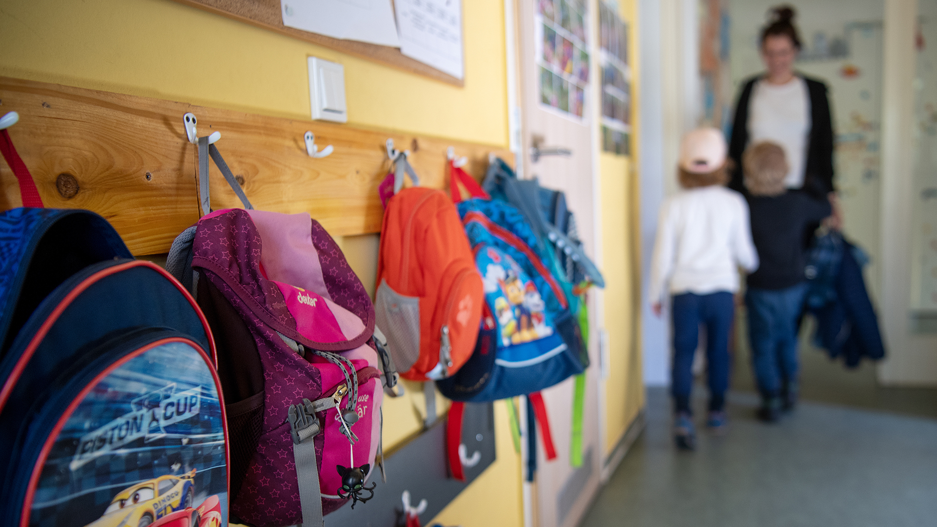 Kinderrucksäcke hängen im Eingangsbereich eines Kindergartens. | dpa