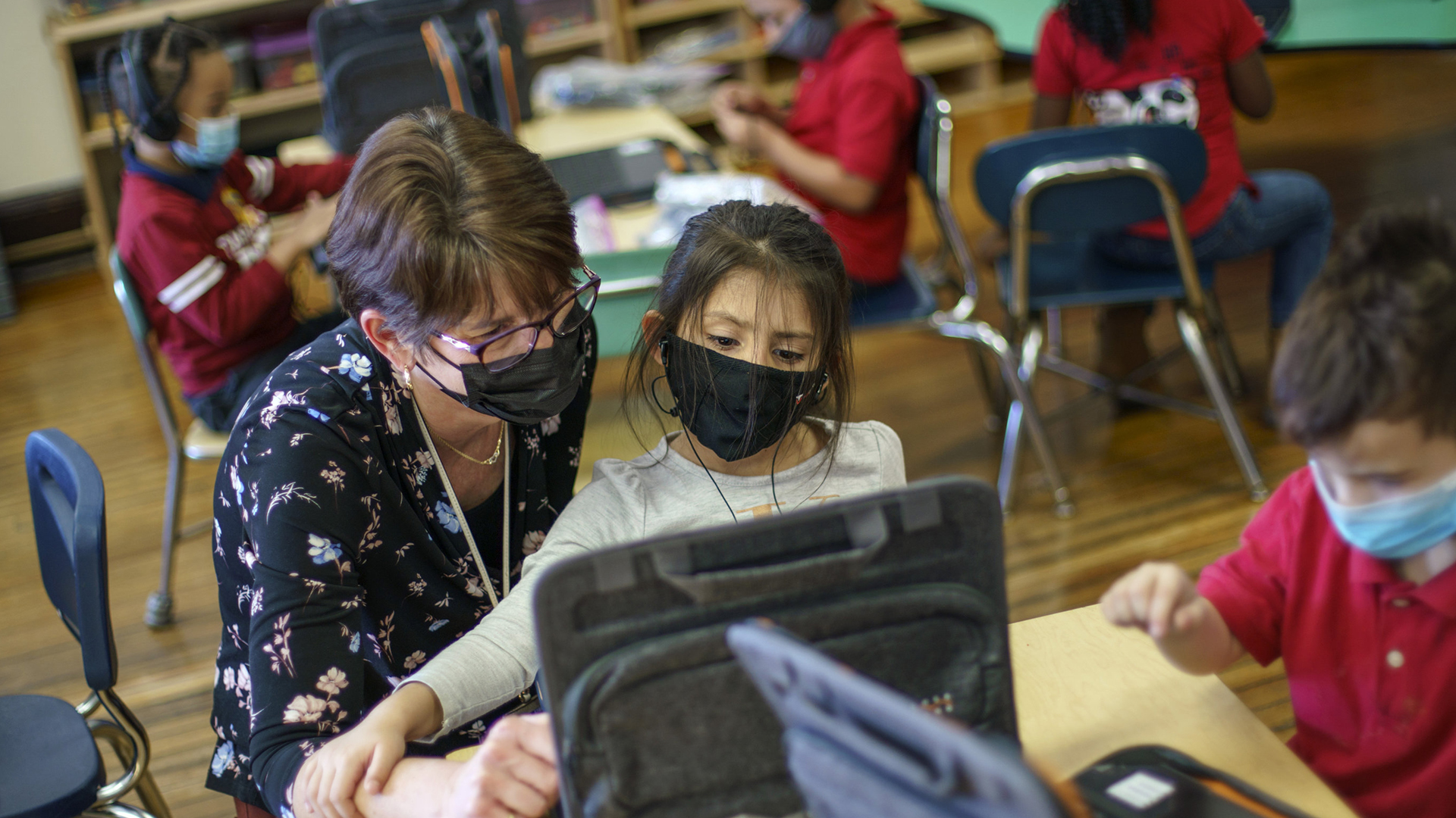 Eine Kindergärtnerin arbeitet mit einem Kind am Computer. | AP