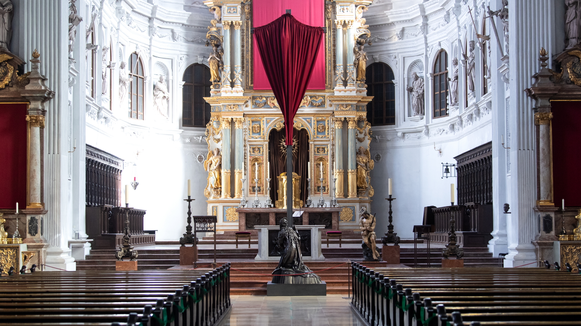 Ein rotes Tuch verhüllt vor Ostern in der St. Michael Kirche in München das Kreuz vor dem Altar.  | dpa