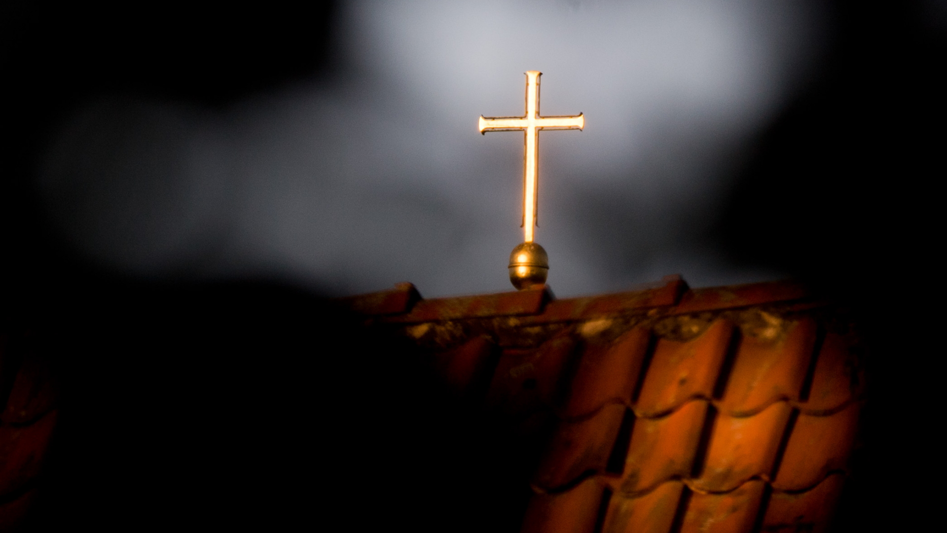 Ein goldenes Kreuz ist auf einem roten Ziegeldach angebracht. | Bildquelle: dpa