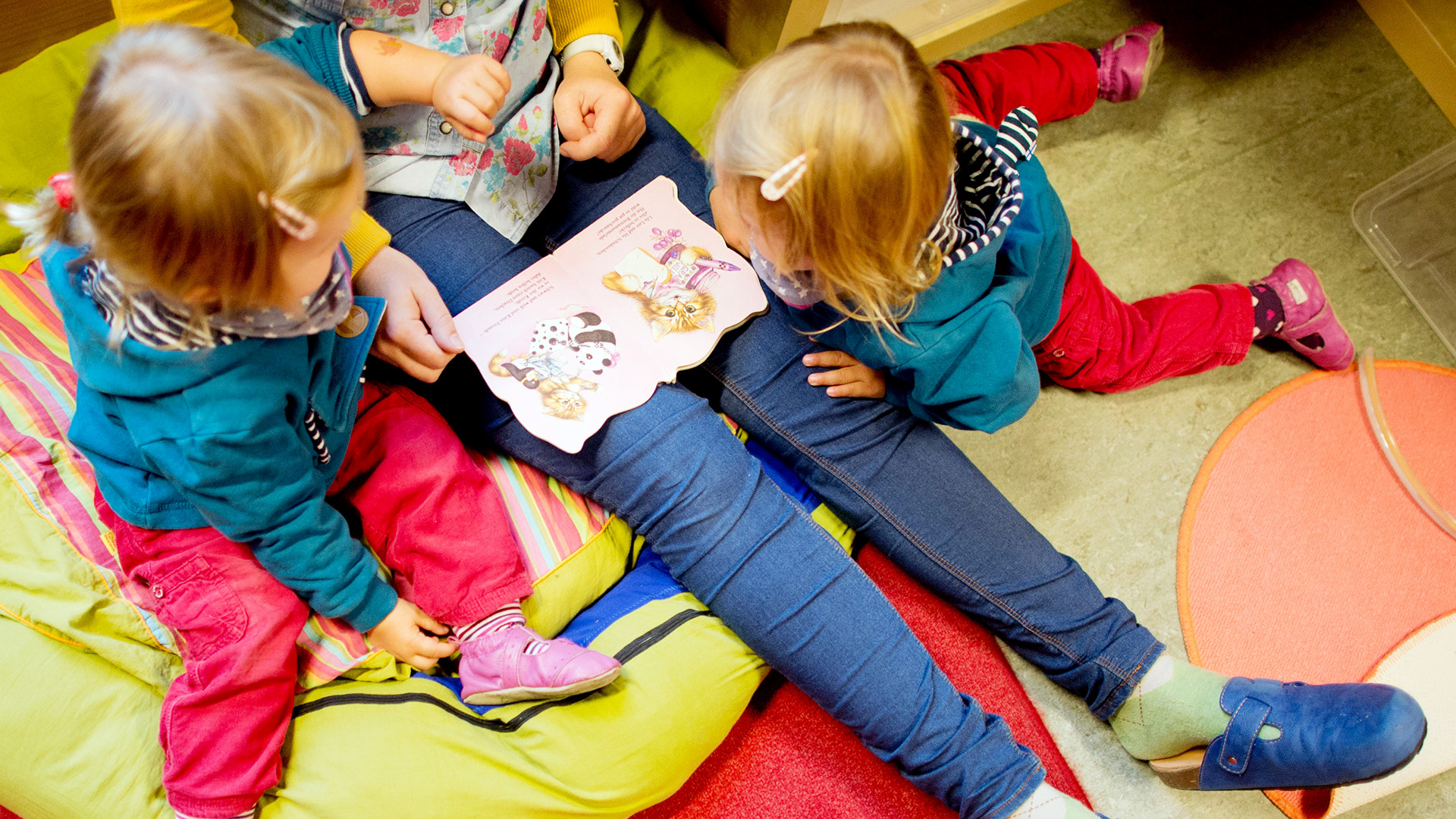 Eine Erzieherin liest mit Zwillingen ein Buch in einer Kindertagesstätte | dpa