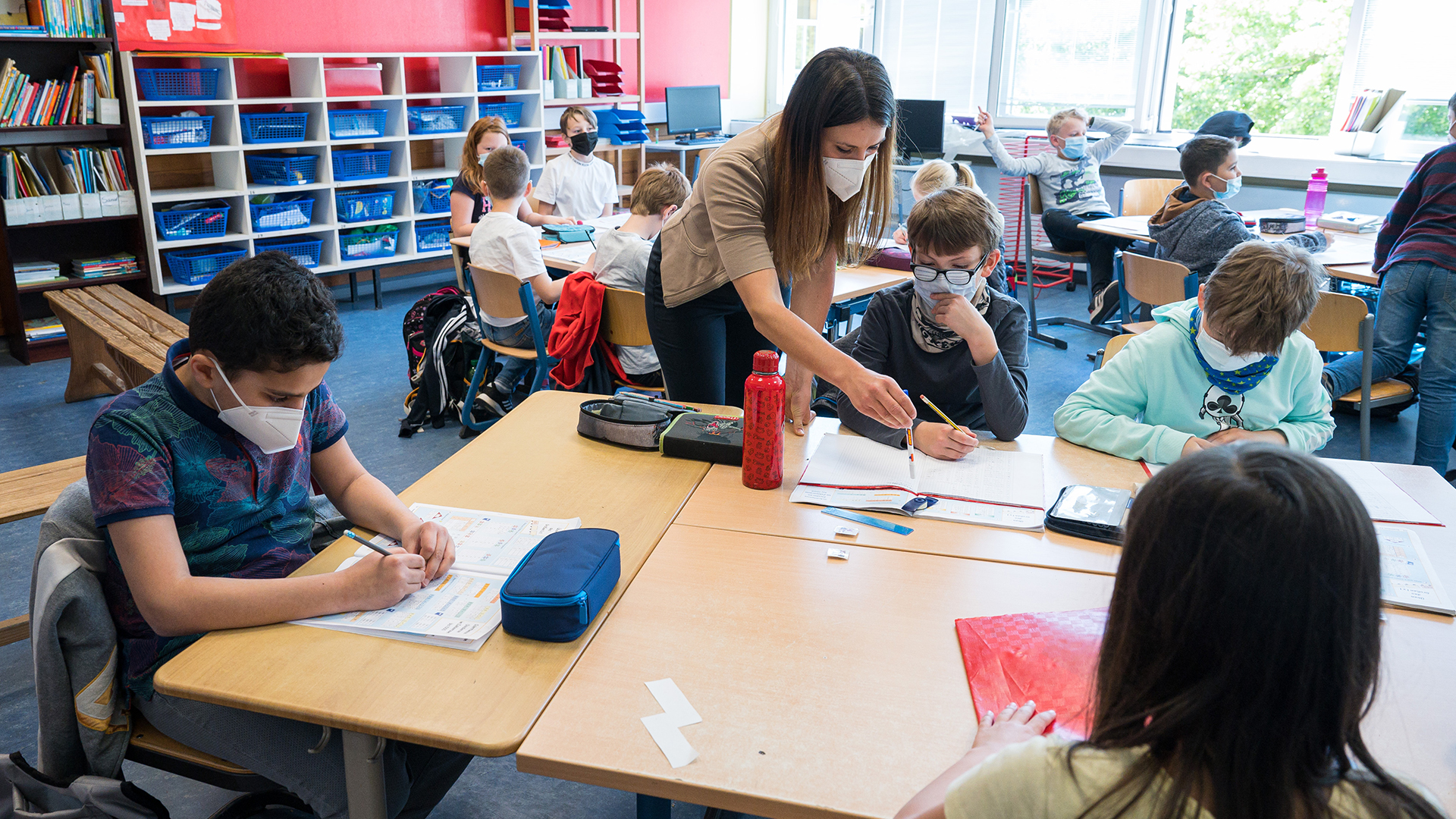 Eine Klassenlehrerin mit Schülerinnen und Schülern im Klassenzimmer - alle tragen einen Mund-Nasen-Schutz. | picture alliance/dpa