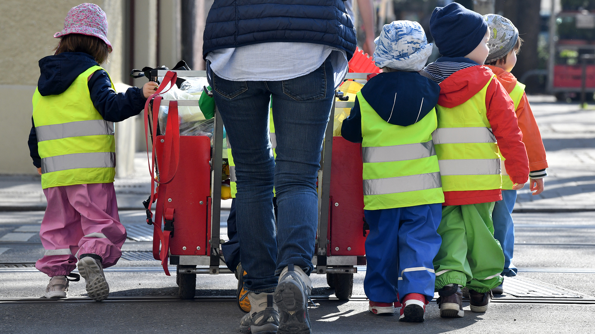 Eine Betreuerin läuft mit mehreren Kleinkindern über einen Bürgersteig.  | dpa