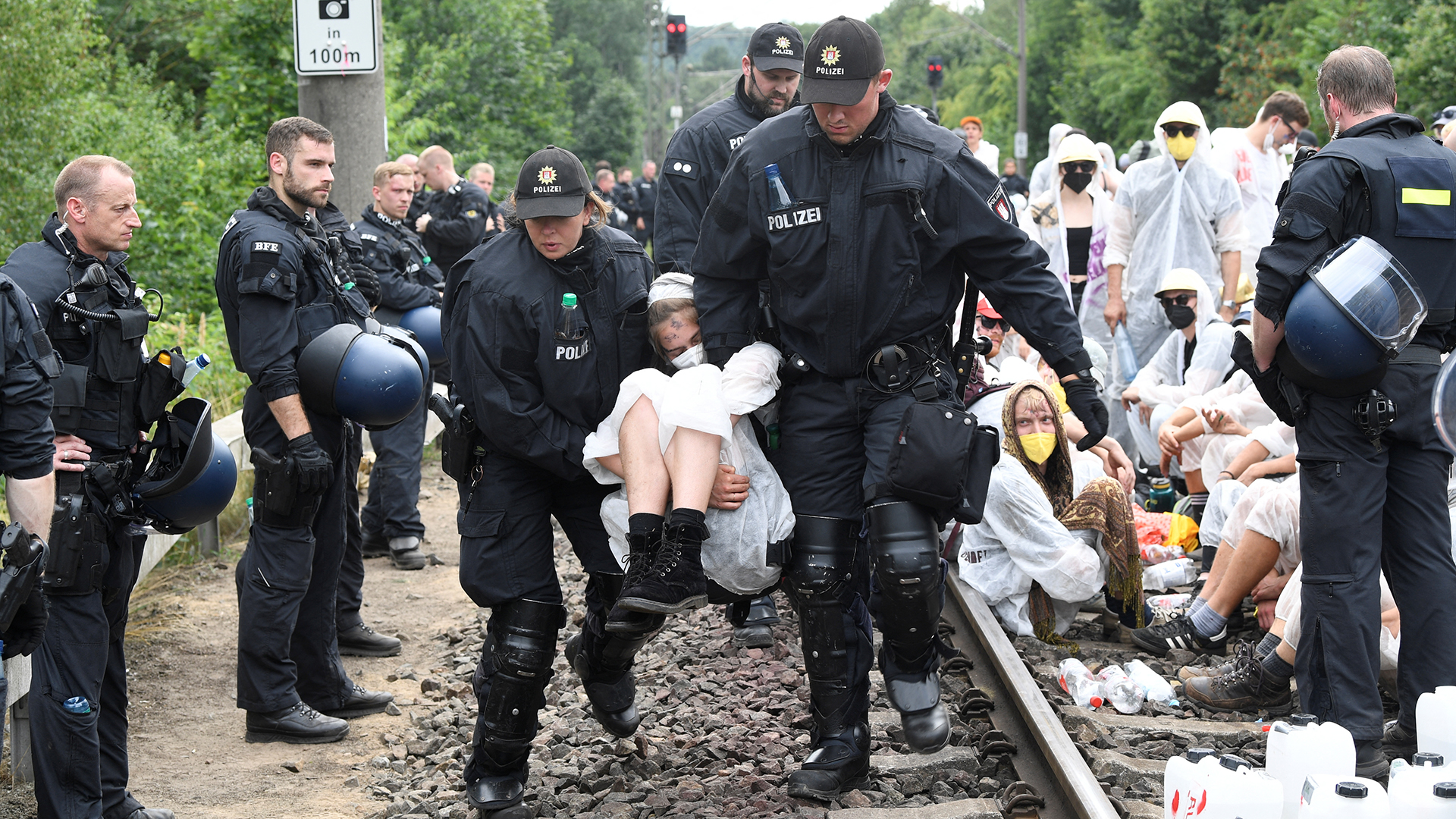 Polizisten tragen eine Klima-Aktivistin von den Gleisen.