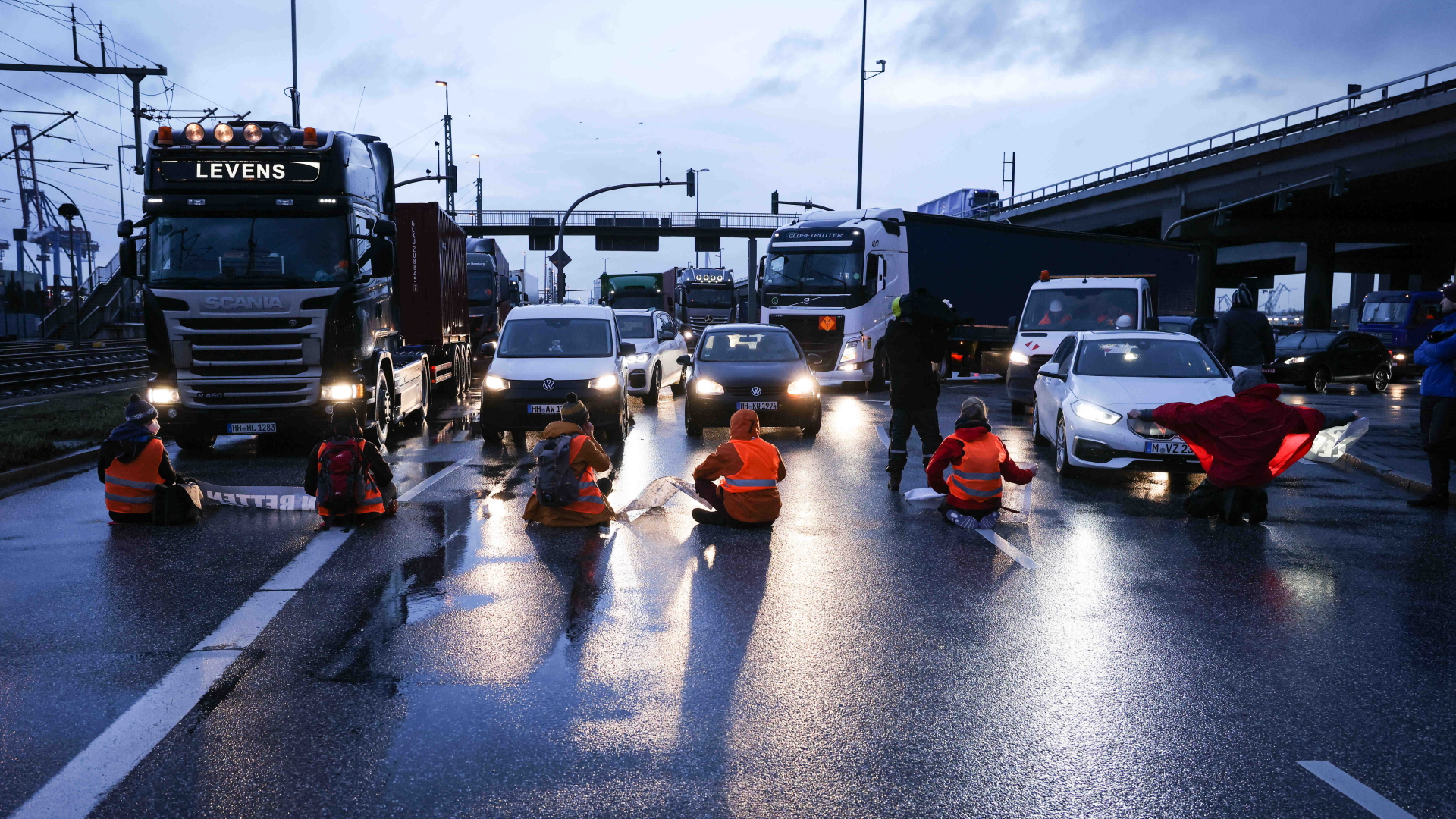Klimaaktivisten der Aktion "Aufstand der letzten Generation" blockieren am 21. Februar 2022 in Hamburg eine Kreuzung zur Köhlbrandbrücke und zur Autobahn A7 | dpa
