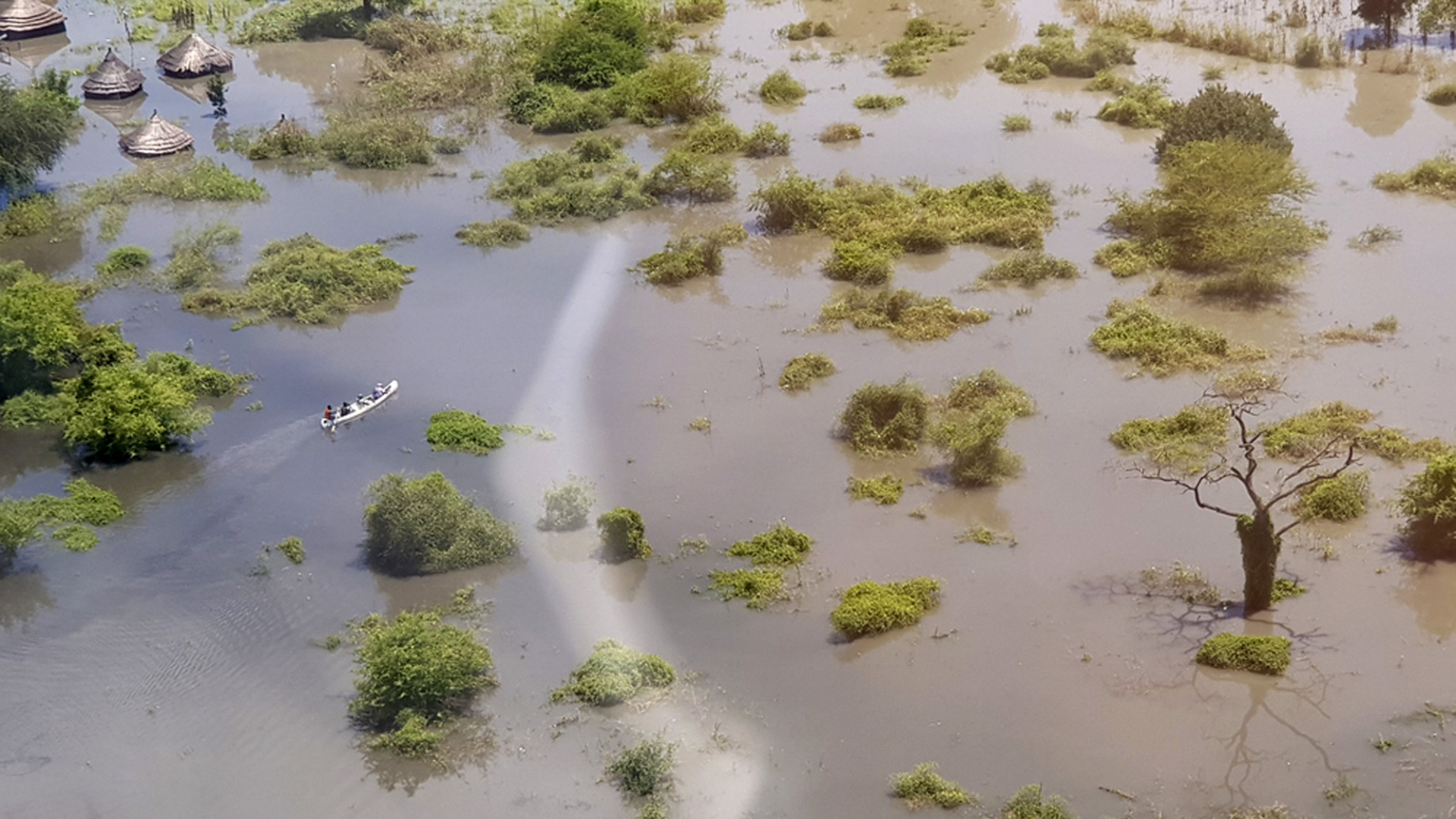 Menschen bewegen sich im Südsudan in einem Boot durch die überschwemmte Landschaft fort. | AP
