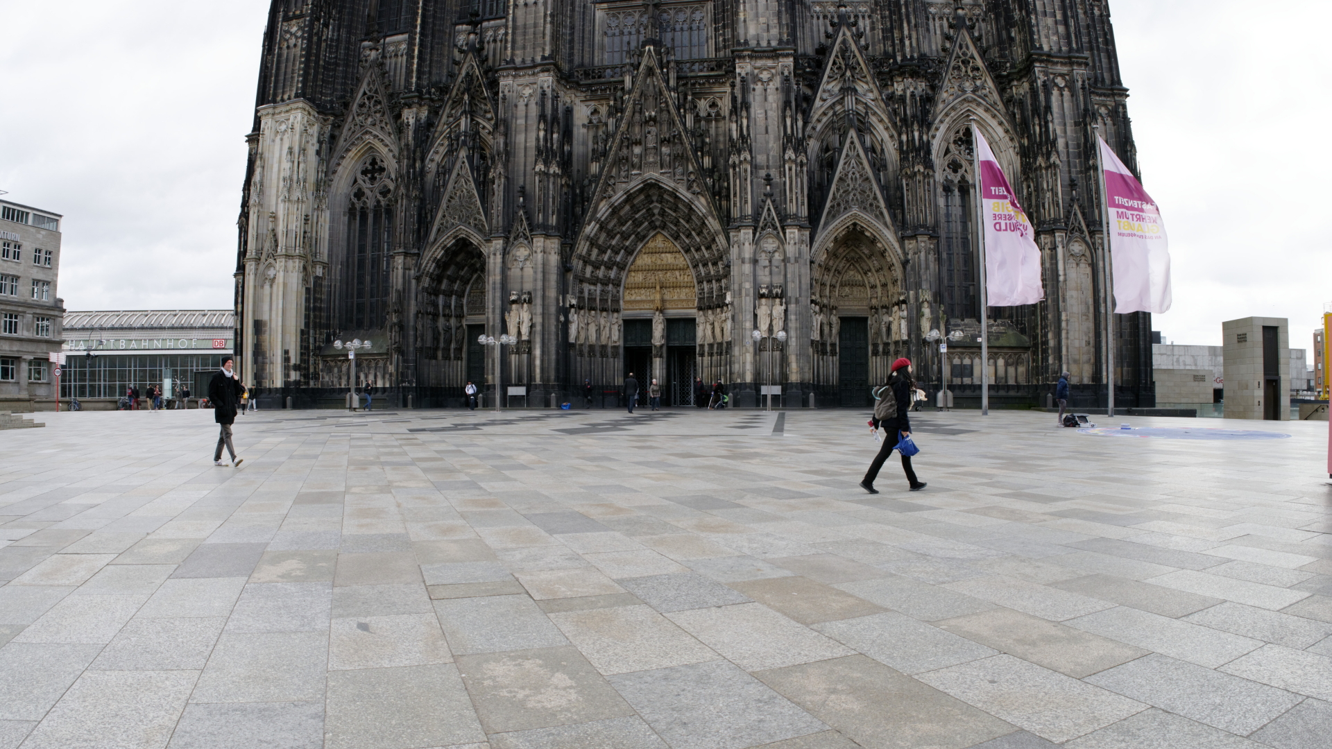Nur wenige Menschen gehen auf dem Platz vor dem Kölner Dom, der sonst voller Touristen ist.  | dpa
