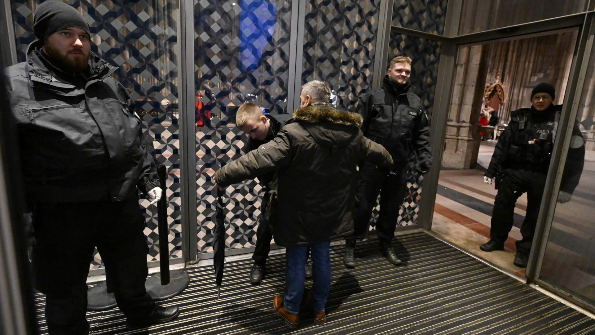 Polizisten durchsuchen am Eingang des Kölner Doms einen Mann.
