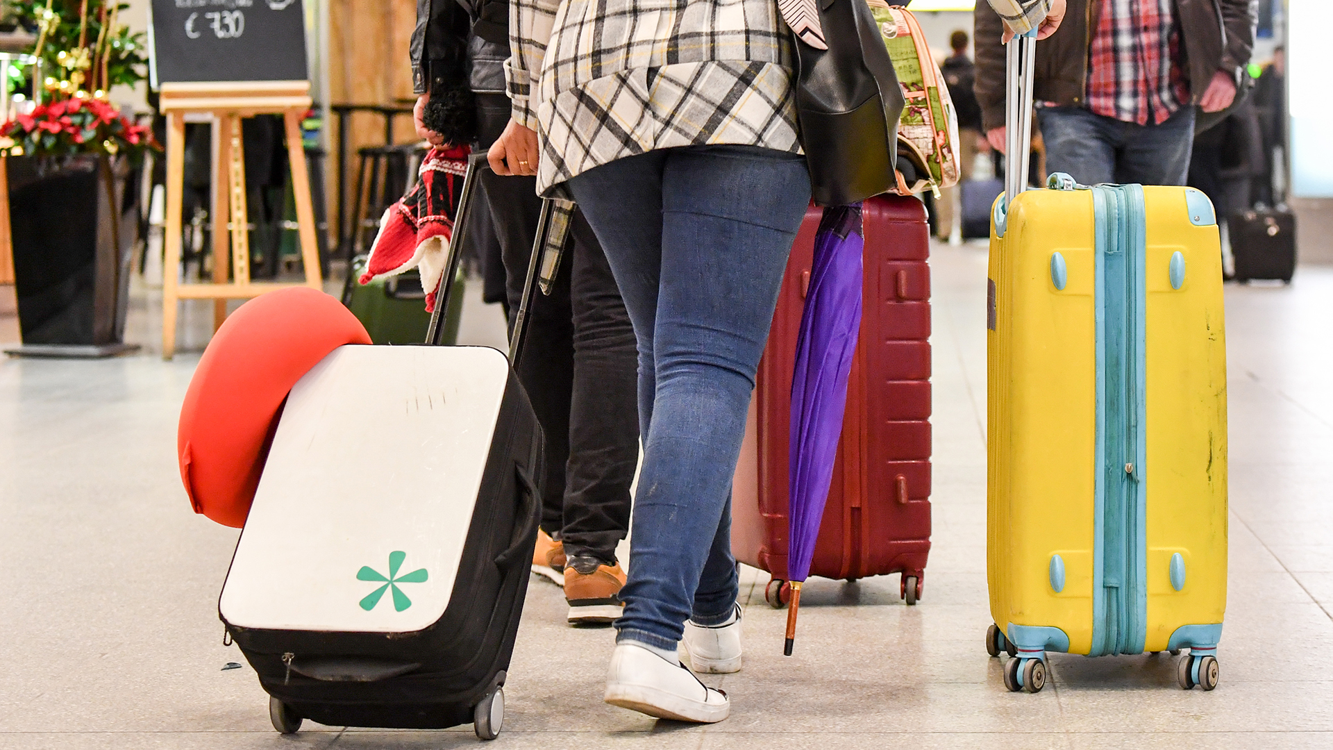 Passagiere gehen mit ihren Koffern auf dem Flughafen Tegel durch die Ankunftshalle im Flughafengebäude. | dpa