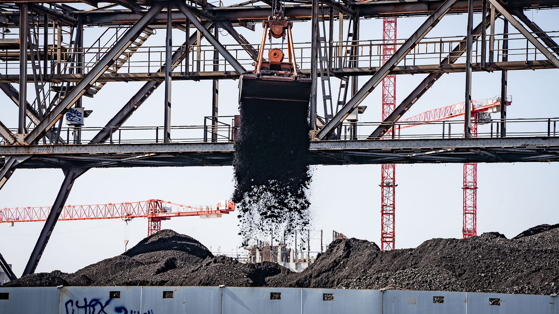 Ein Bagger entlädt Kohle von einem Binnenschiff auf eine Halde neben einem Kraftwerk in Offenbach. | dpa