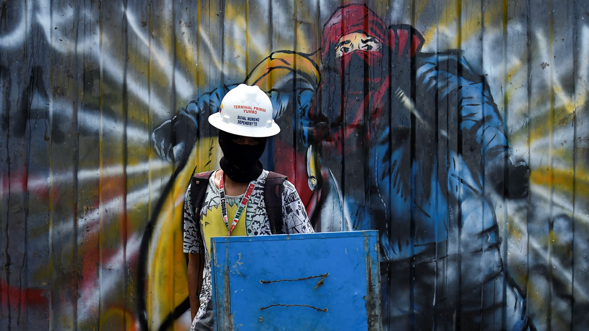 Eine vermummte Person mit einem Blechschild in Kolumbien. | AFP