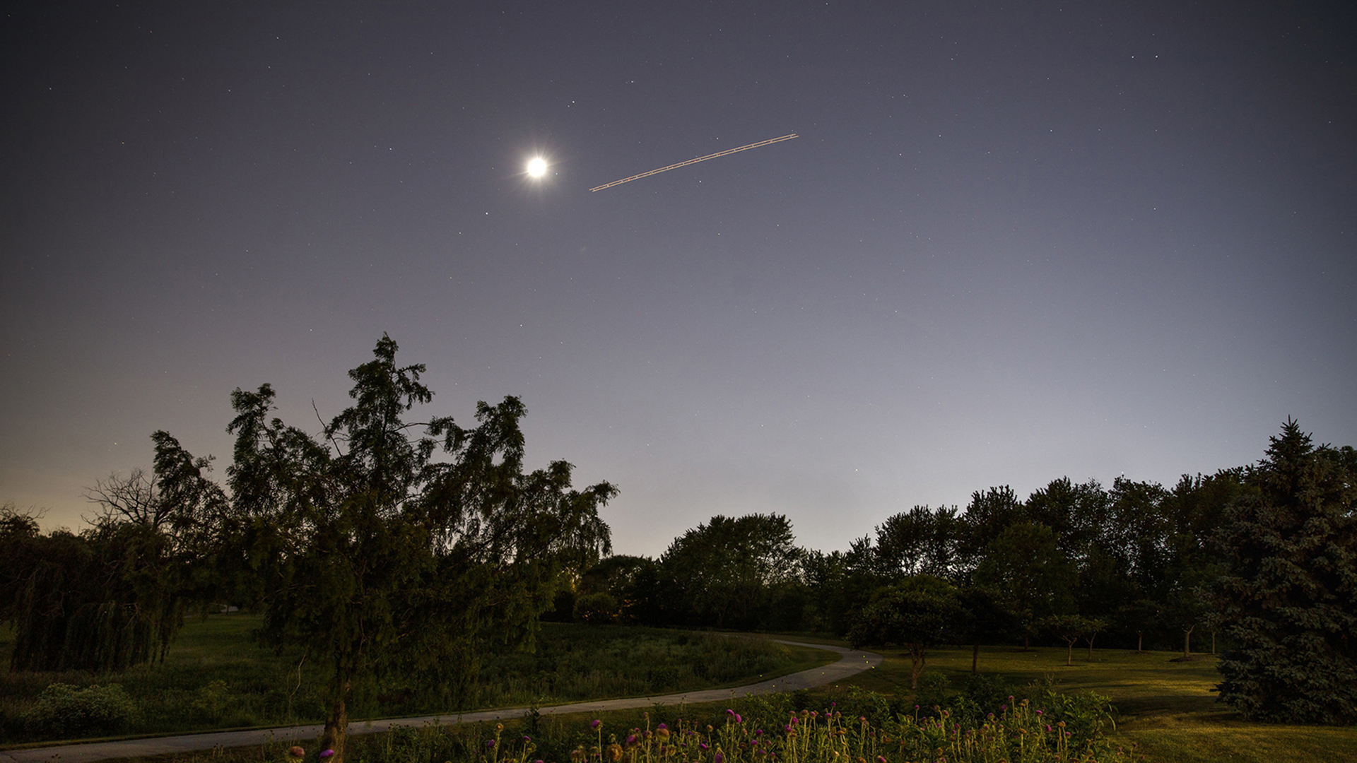 Ein Flugzeug zieht über den Nachthimmel von Tinley Park in Illinois. | picture alliance / newscom