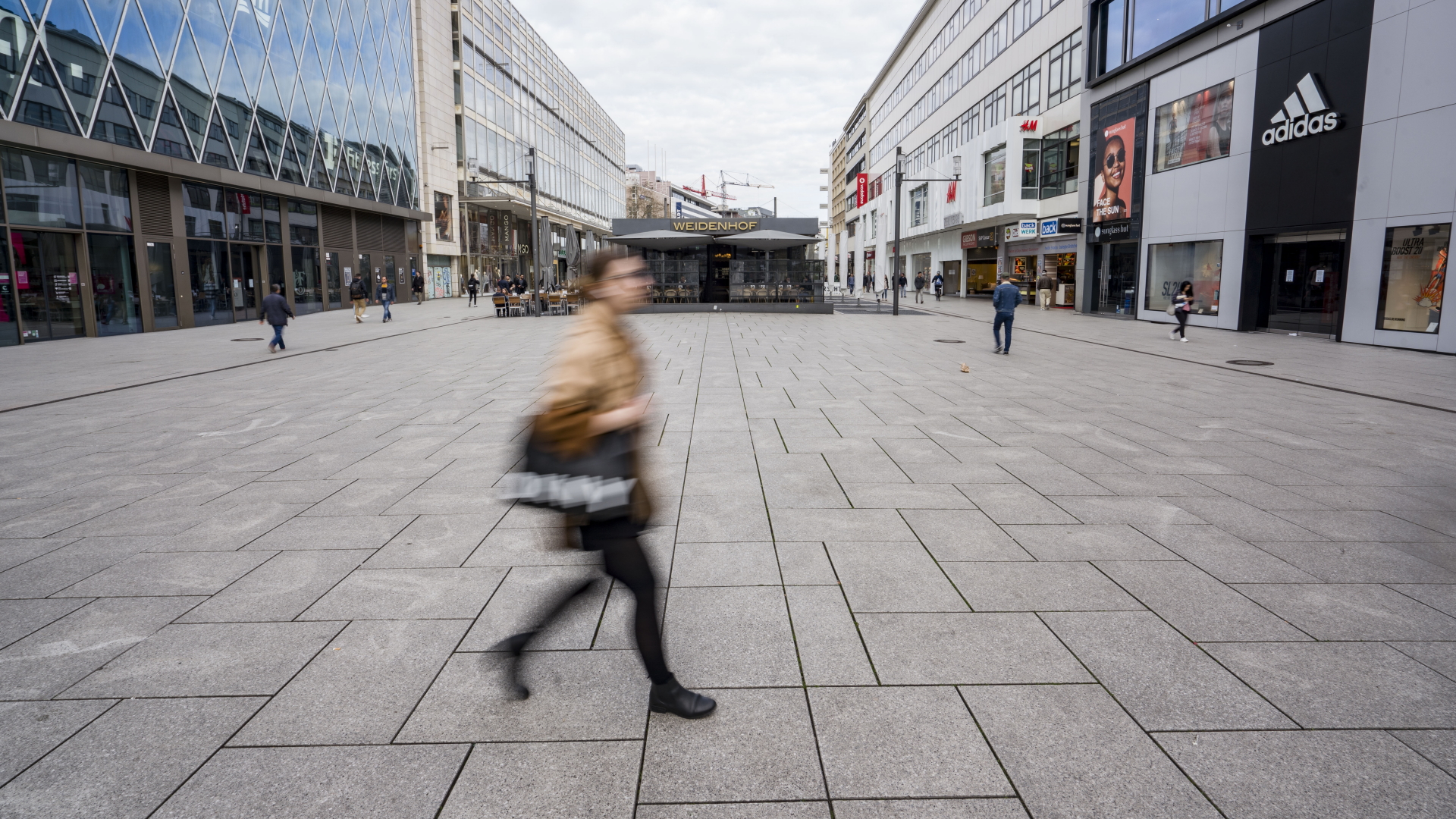 Eine Frau läuft durch eine nahezu leere Einkaufsstraße in Frankfurt. | dpa