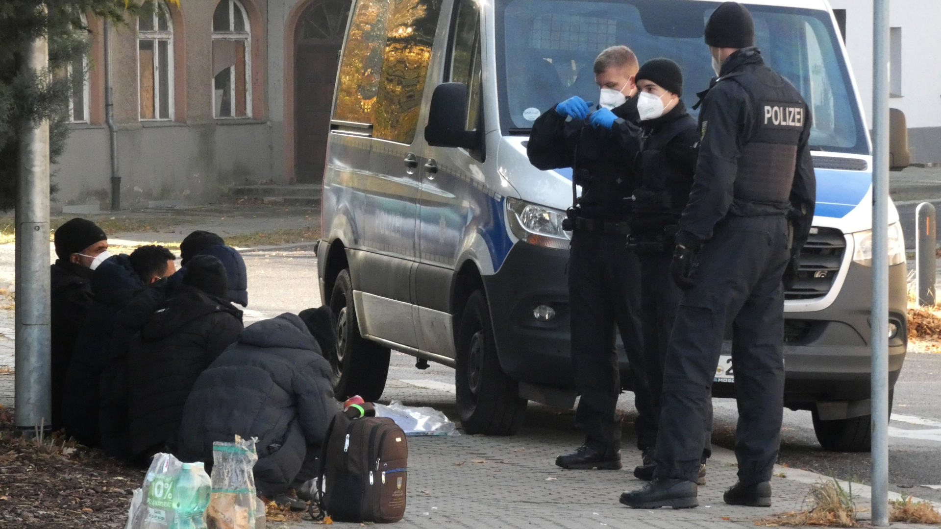 Bundespolizisten stehen an einem Polizeifahrzeug vor Geflüchteten in Guben, Brandenburg (Archivbild vom 24. Oktober 2021) | dpa