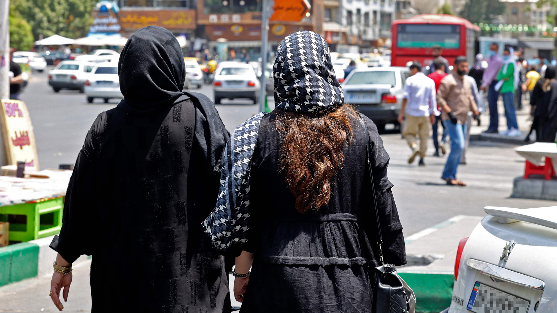 Frauen mit Kopftuch laufen auf einer Straße in Teheran. | AFP