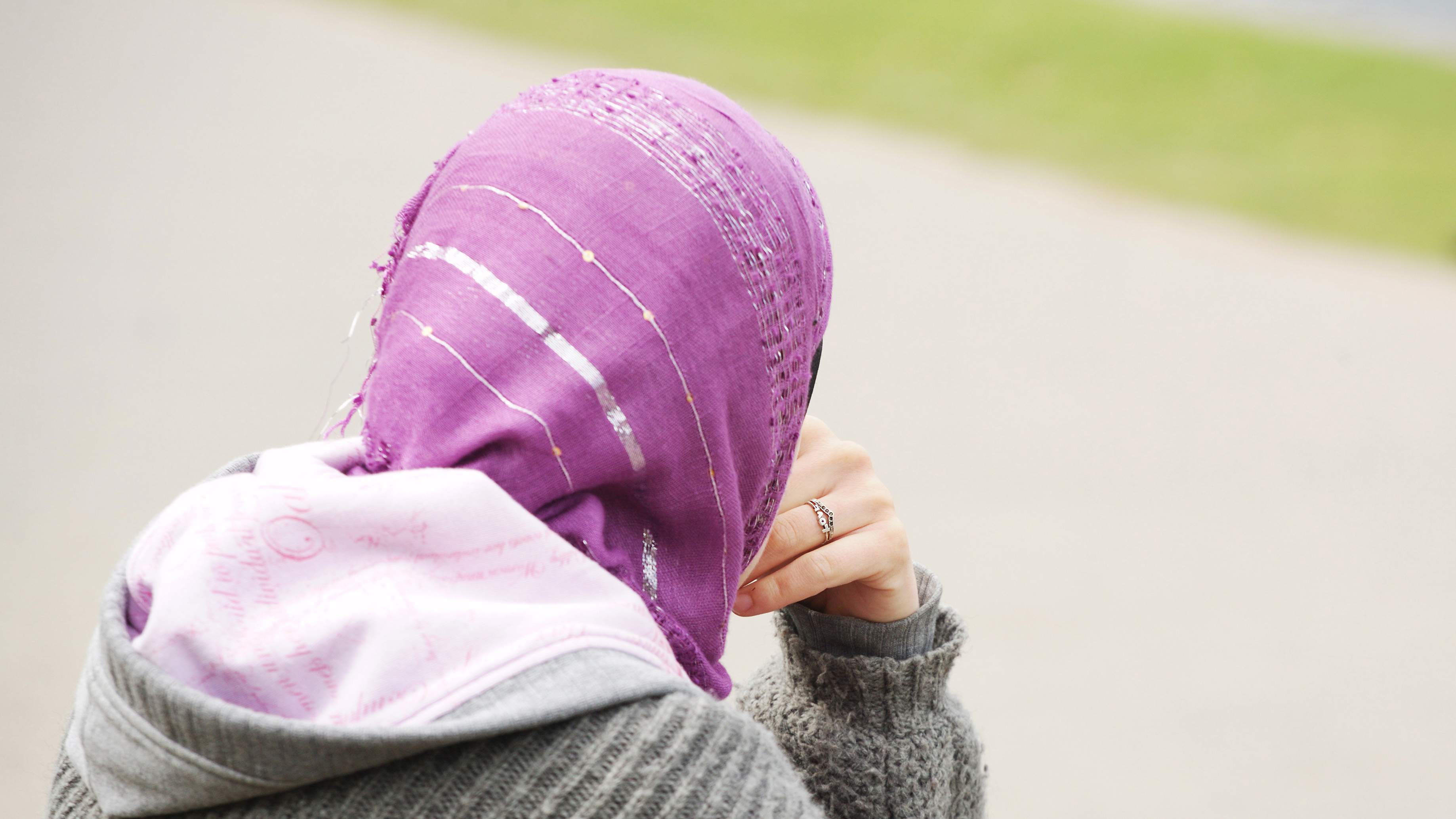Eine junge Frau mit Kopftuch sitzt an einem Weg. | dpa
