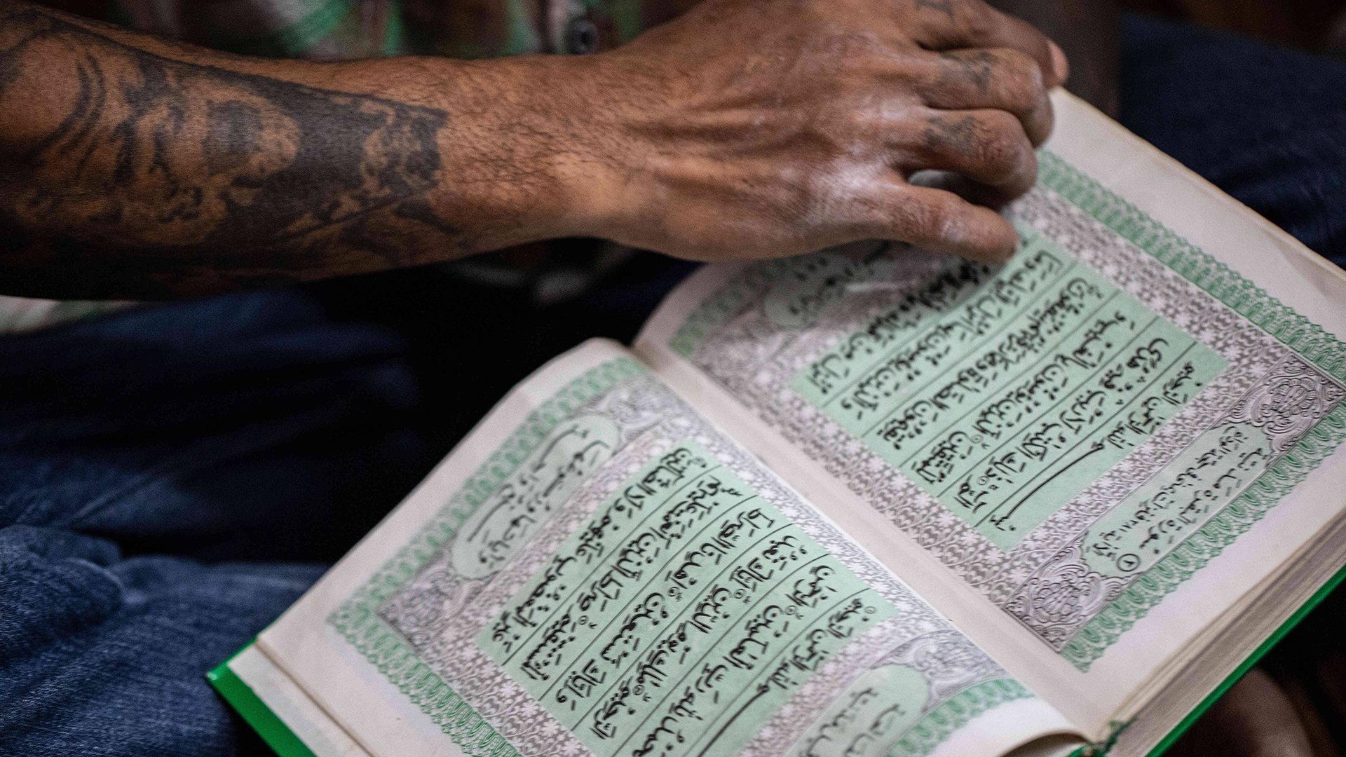 Eine Hand blättert eine Seite in einem Koran um. | imago images/ZUMA Wire