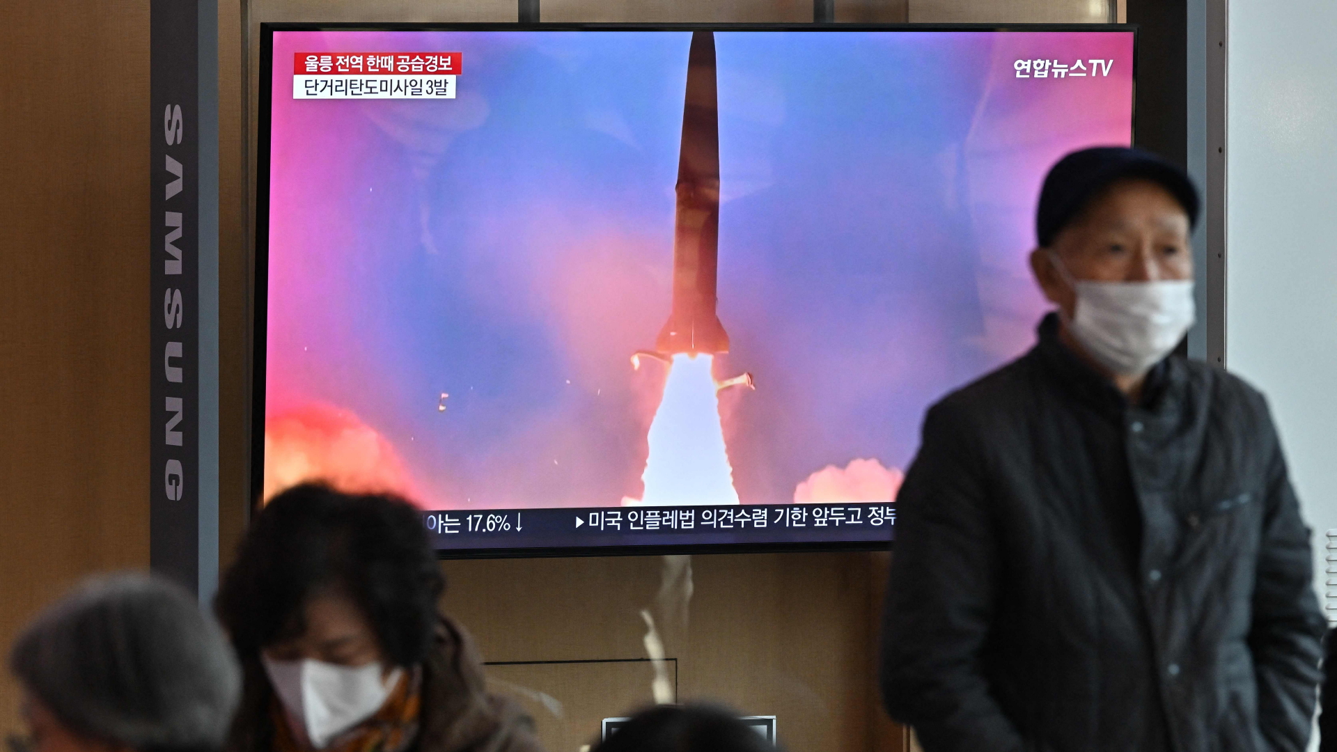 Menschen schauen sich einen Fernsehbildschirm an, auf dem eine Nachrichtensendung mit Filmmaterial eines nordkoreanischen Raketentests an einem Bahnhof in Seoul gezeigt wird | AFP