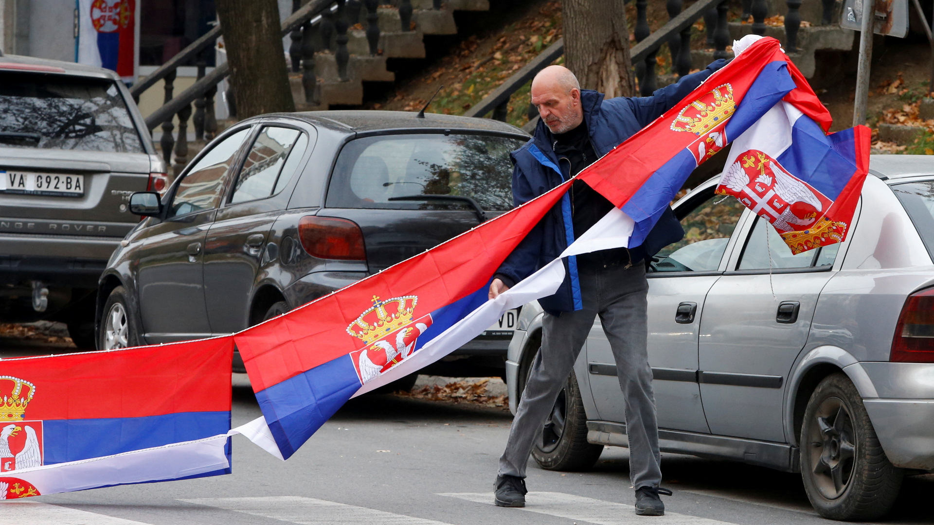 Ein Mann hängt eine serbische Flagge auf | REUTERS