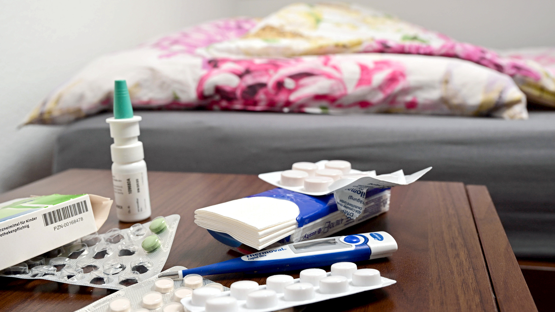 Medikamente und Taschentücher liegen auf einem Nachttisch