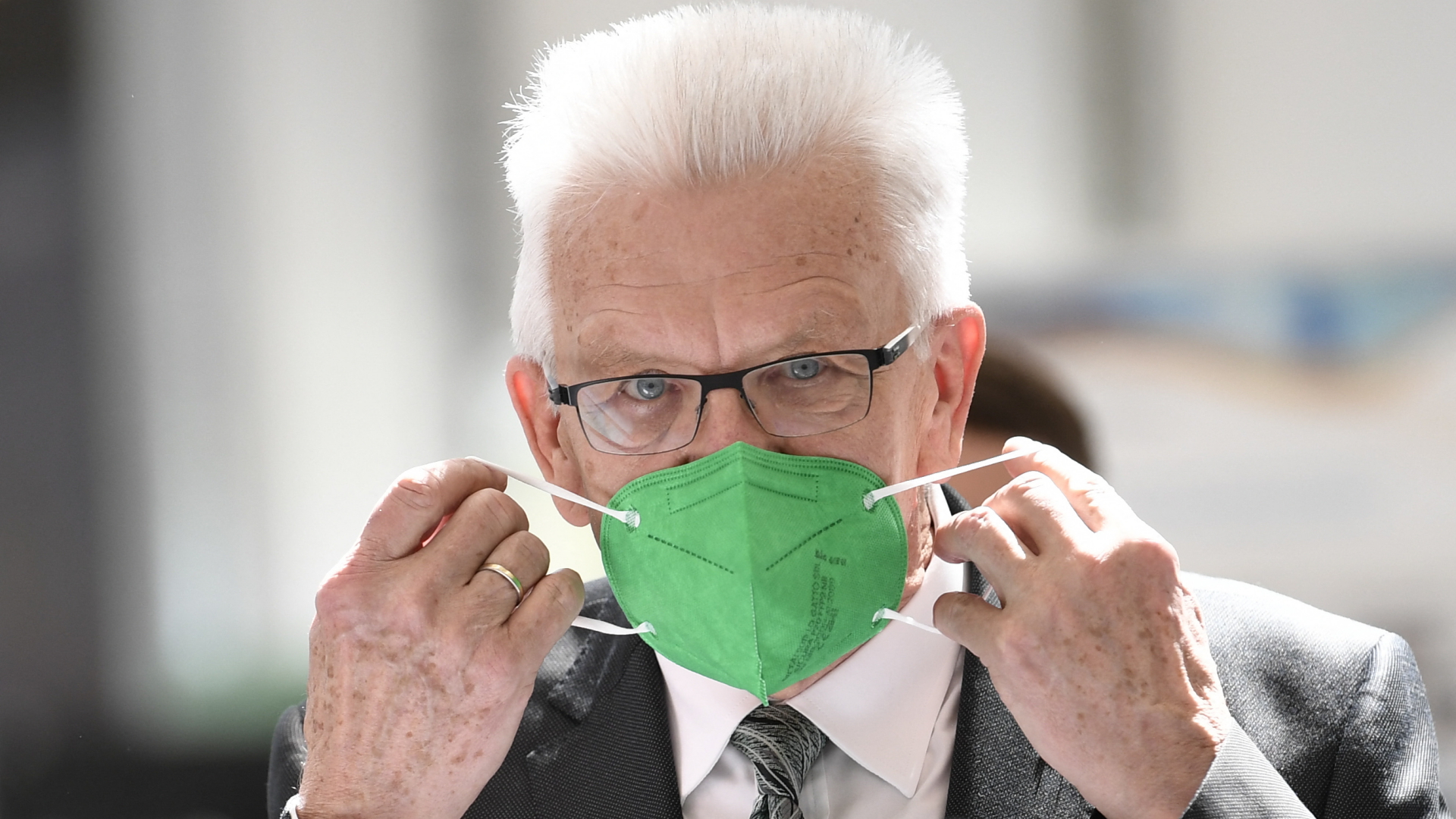 Ministerpräsident Winfried Kretschmann (Grüne) mit einer grünen Maske. | AFP