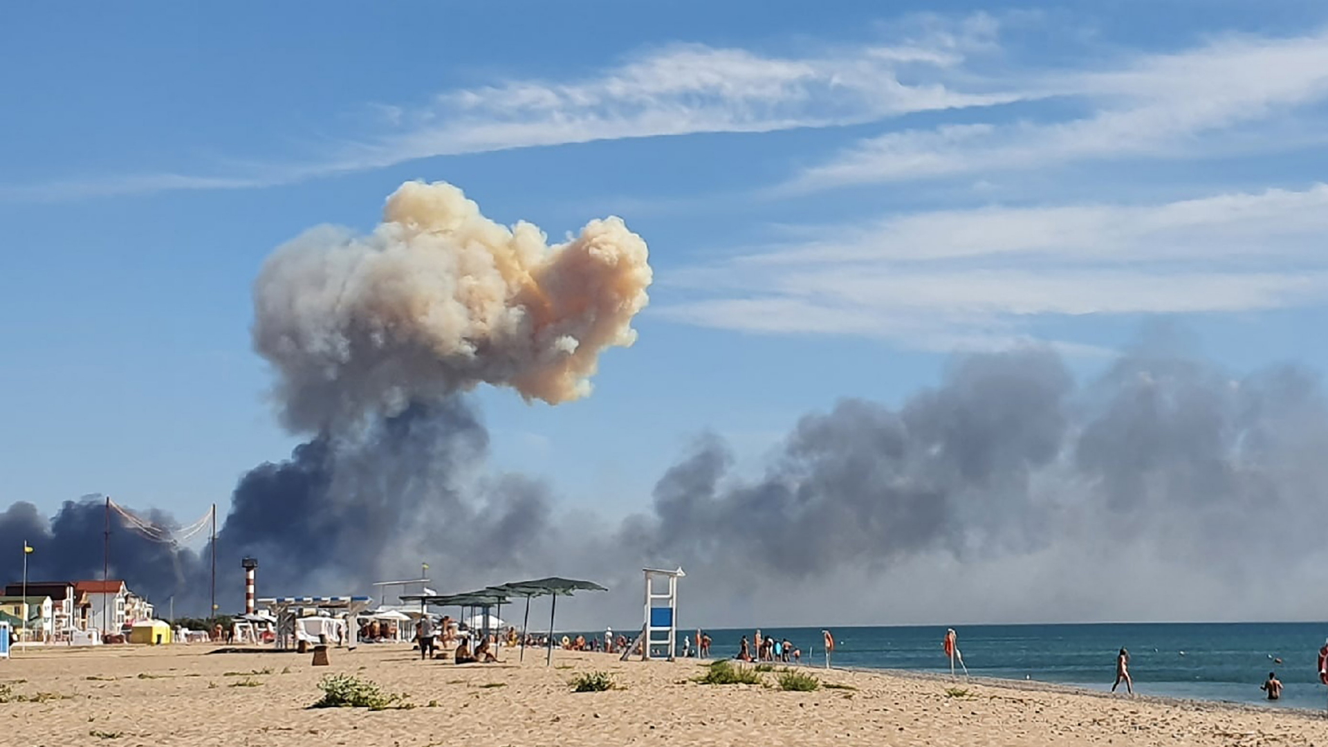 Ein Strand auf der besetzten Halbinsel Krim, im Hintergrund steigt eine große Rauchwolke von den Explosionen auf dem Luftwaffenstützpunkt auf. | AP