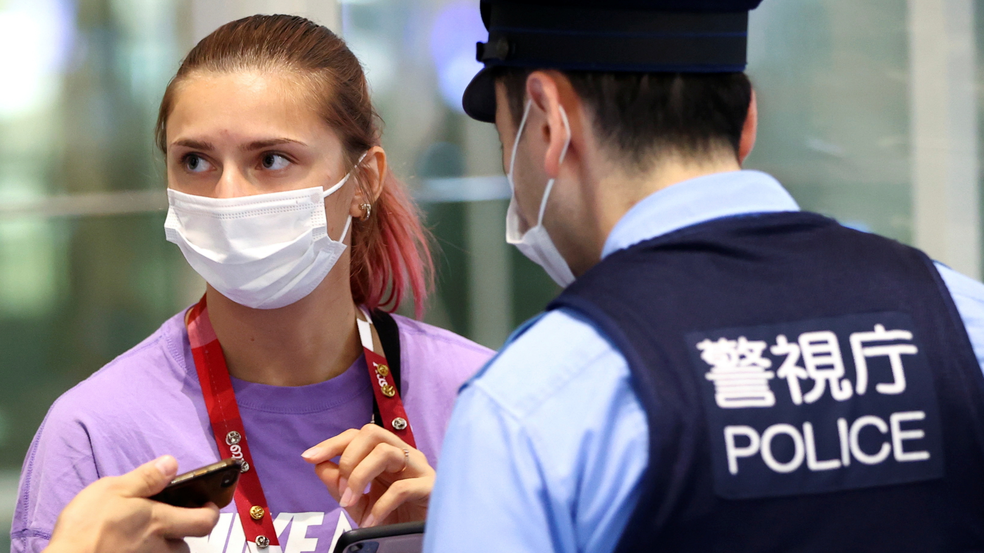 Die belarusische Leichtathletin Kristina Timanowskaja spricht am Flughafen von Tokio mit einem Polizisten.