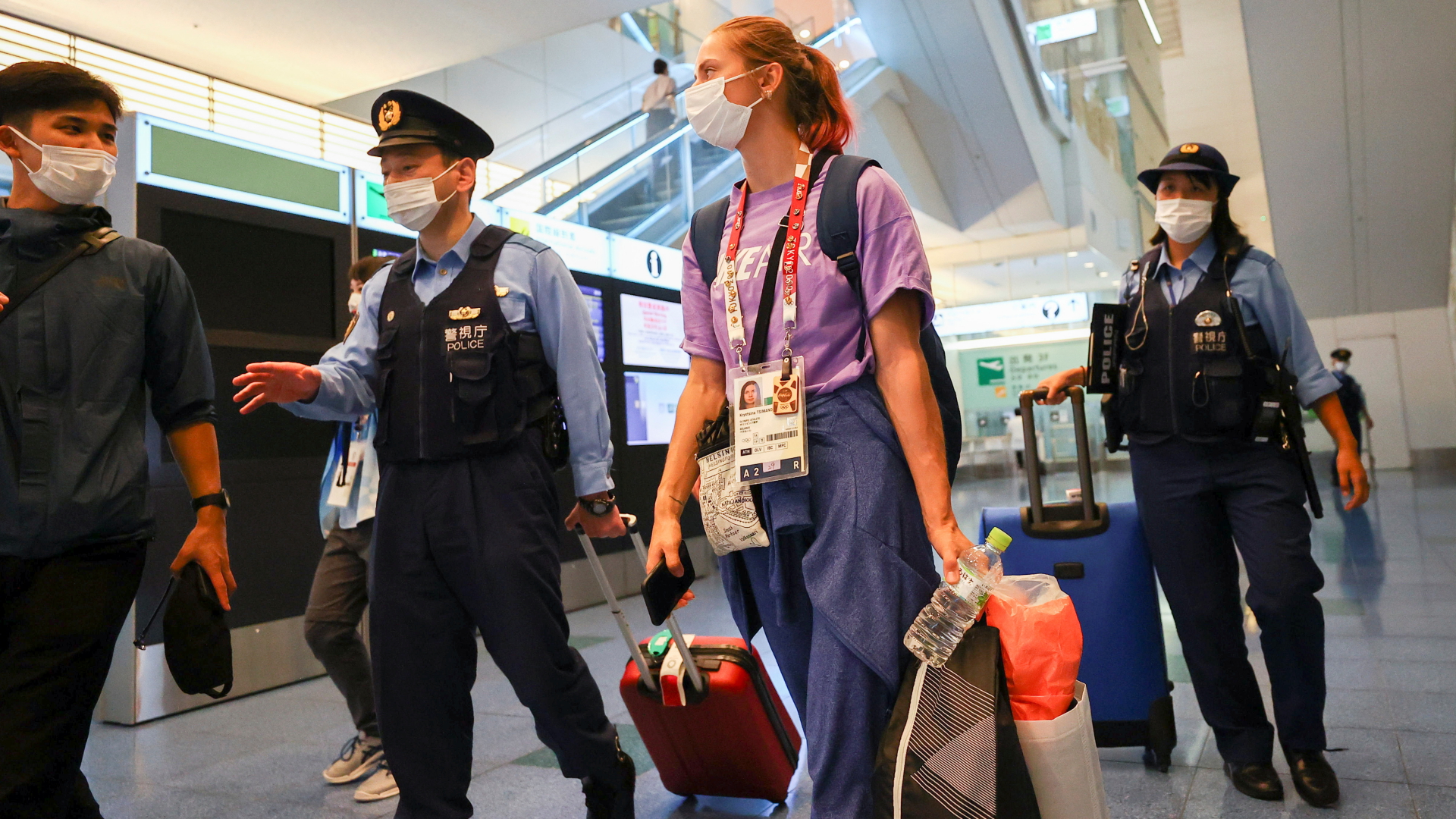 Die belarusische Leichtathletin Kristina Timanowskaja spricht am Flughafen von Tokio mit einem Polizisten. | REUTERS