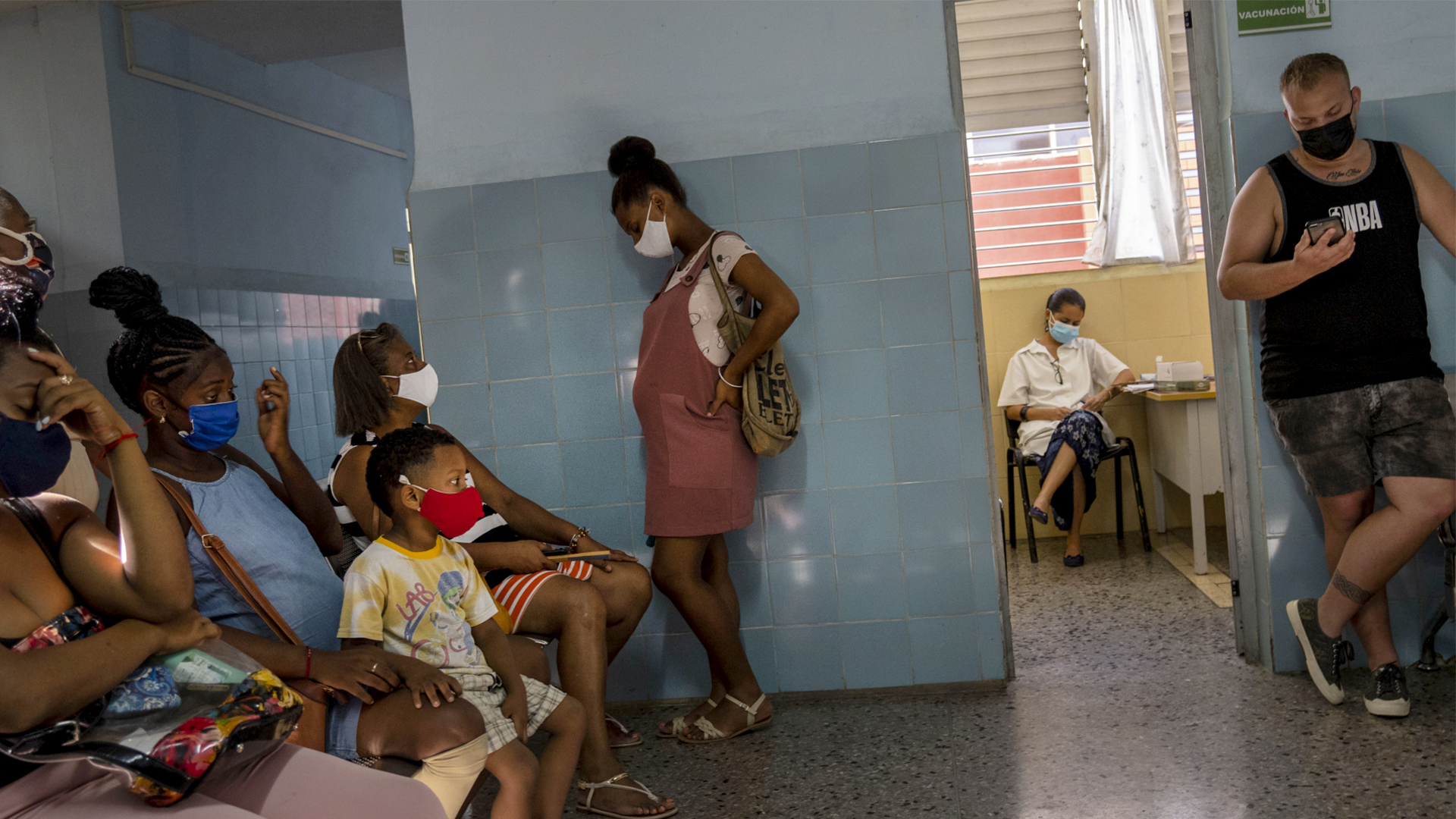 Menschen mit Masken warten in einem Raum auf eine Impfung  | dpa