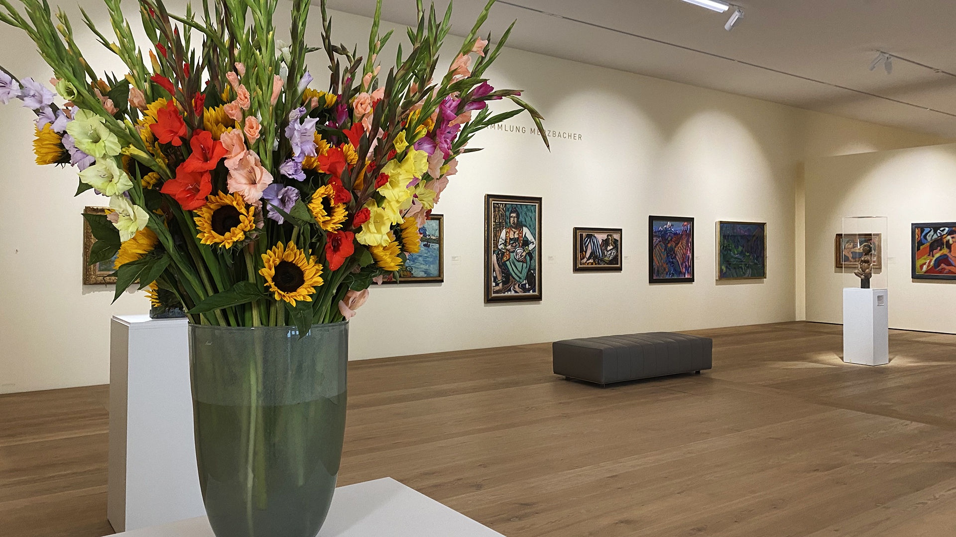 Ein Blumenstrauß steht im Kunsthaus Zürich vor ausgestellten Bildern der Ausstellung Merzbacher. | ARD-Studio Genf