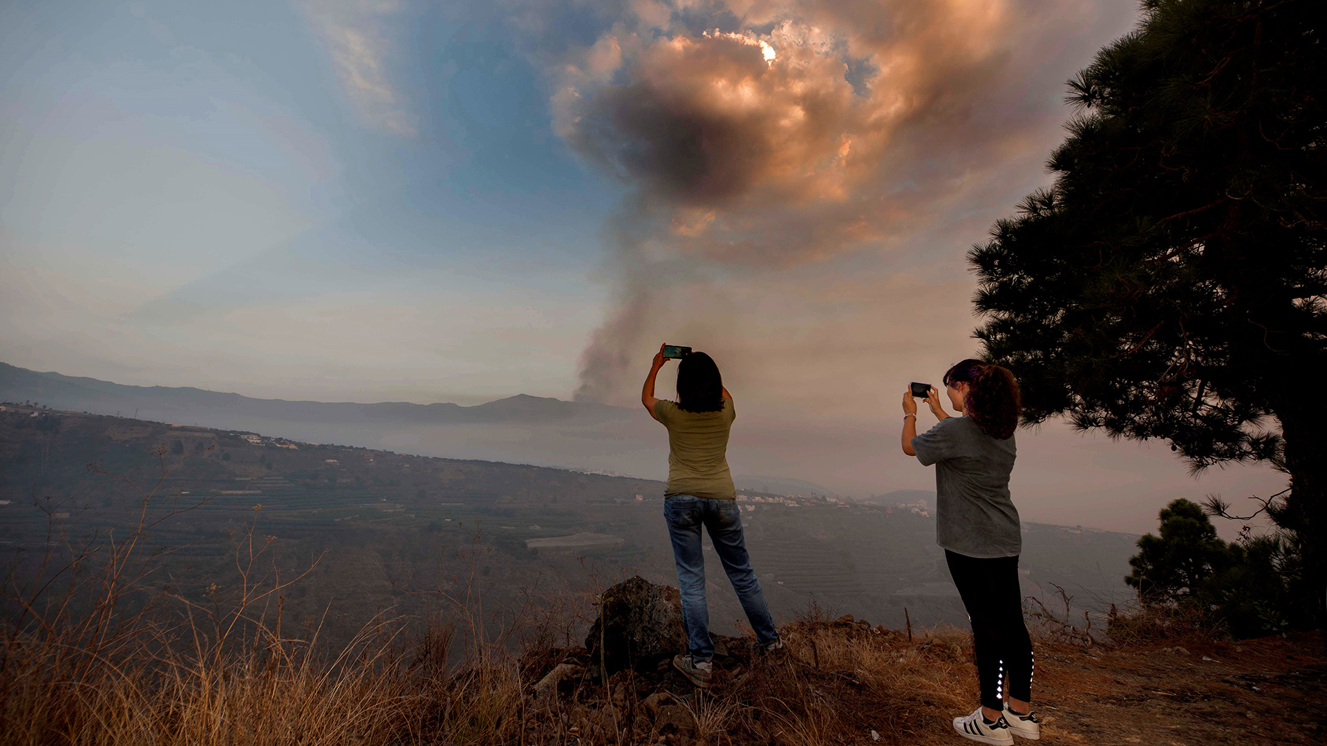 Zwei Frauen fotografieren den aktiven Vulkan vom Valle de Aridane aus, La Palma/Kanarische Inseln. | EPA