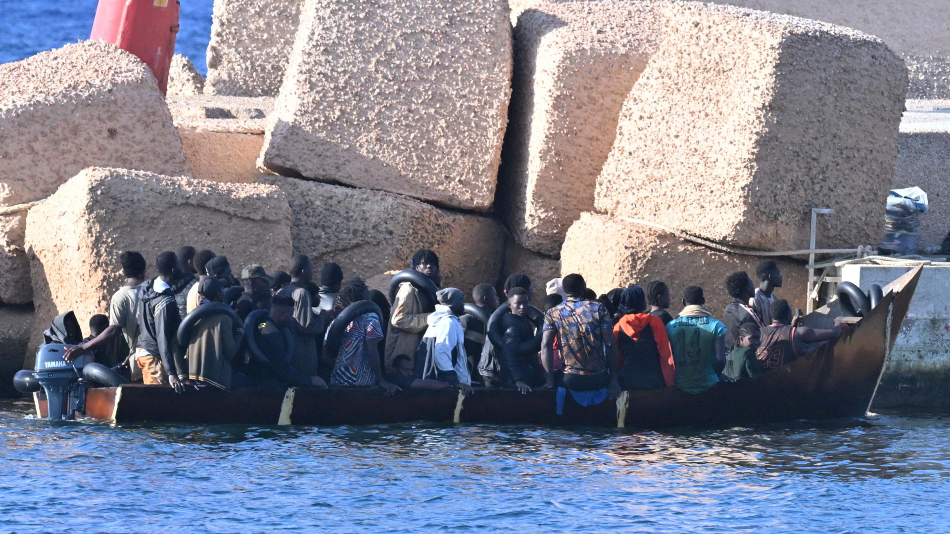 Migranten sitzen in einem Boot vor der italienischen Insel Lampedusa